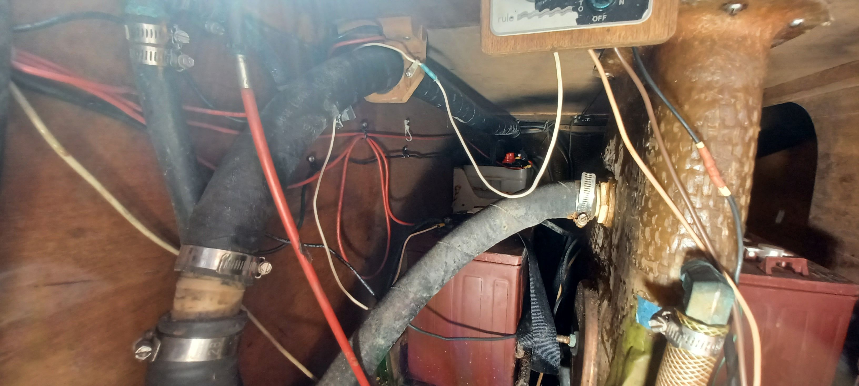 Interior view of a boat engine compartment with hoses and wires.