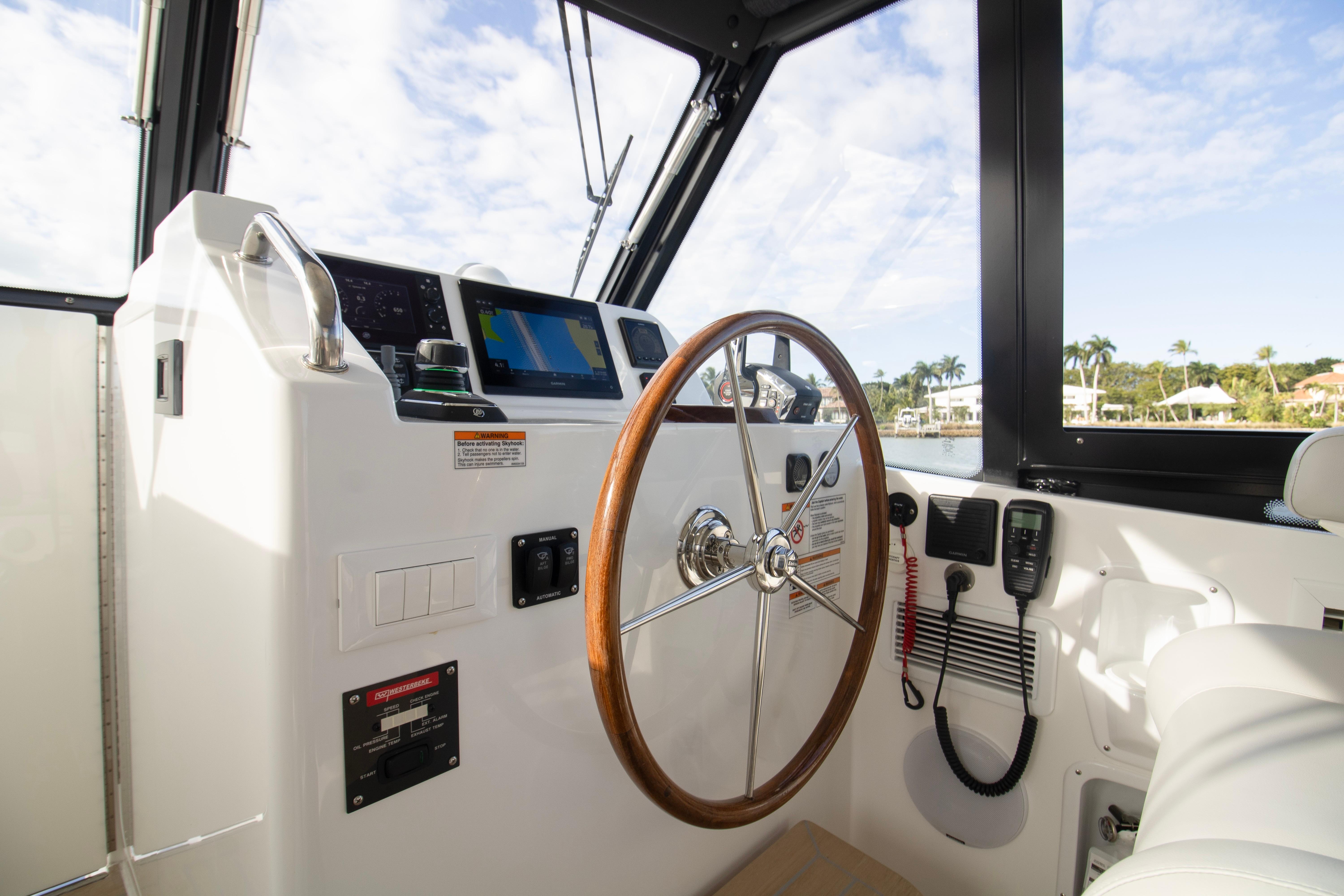 Helm of 2025 MJM 38 X boat with wooden steering wheel and navigation equipment.