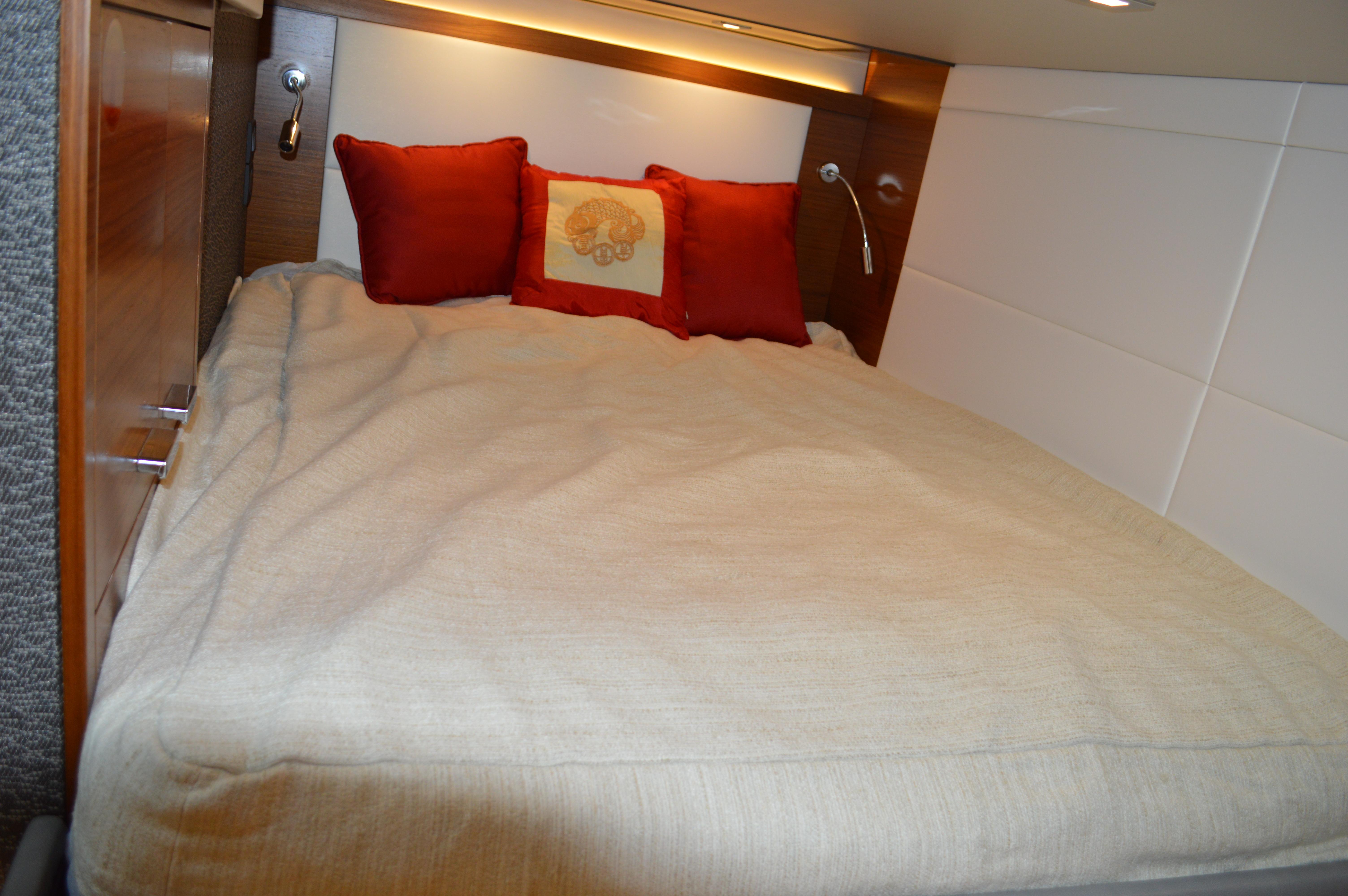 Cozy bedroom in 2019 Tiara Yachts C39 Coupe with red pillows and beige bedding.