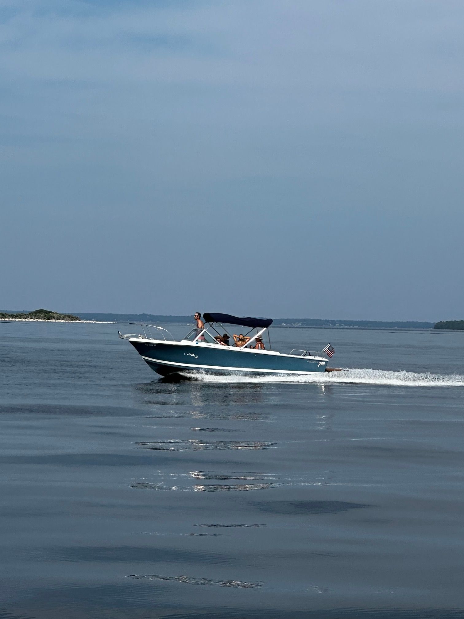 A 1969 John Allmand Citation II cruising on calm water with several people on board.