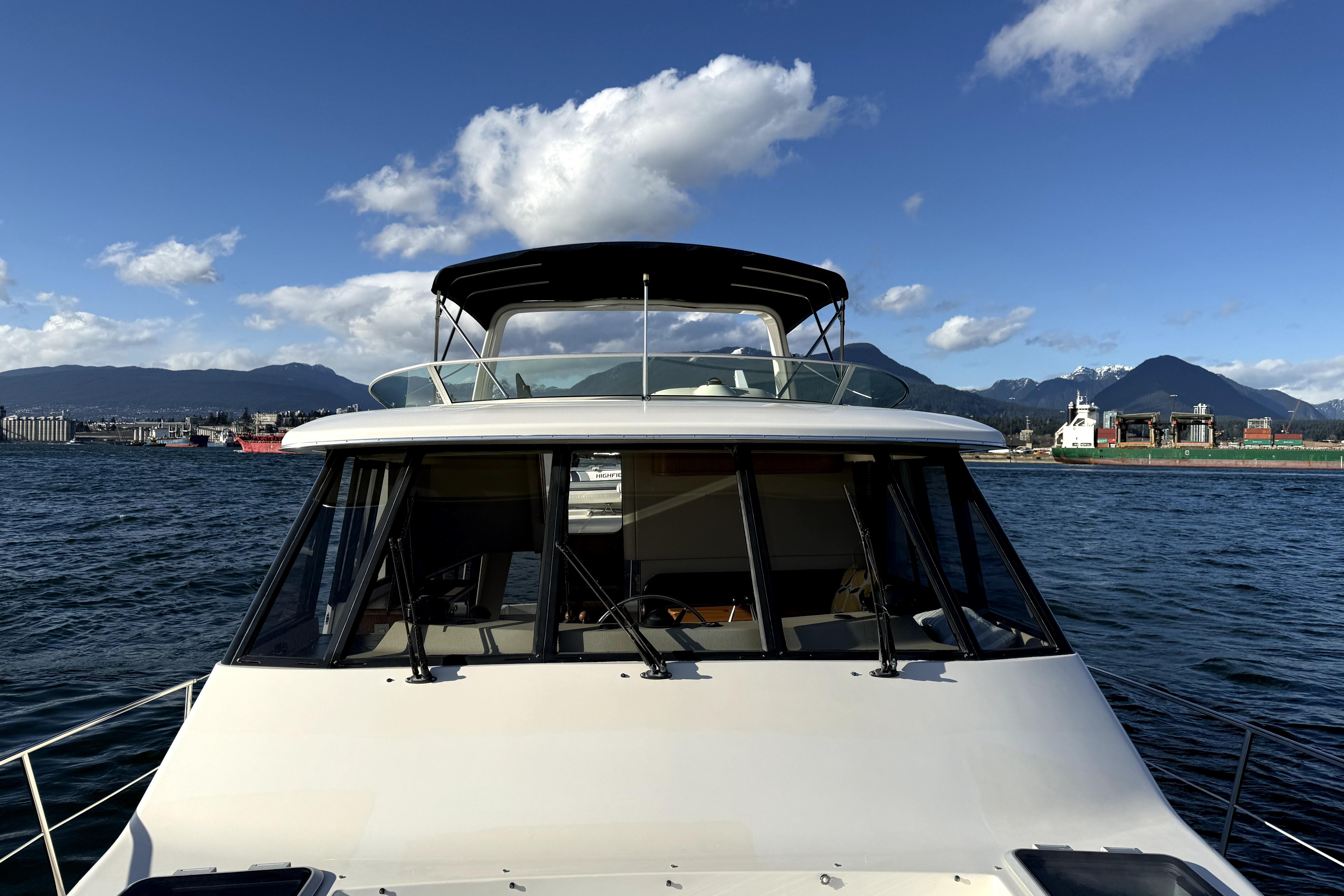 1998 Bayliner 4788 Pilot House Motoryacht on water with mountains in background.