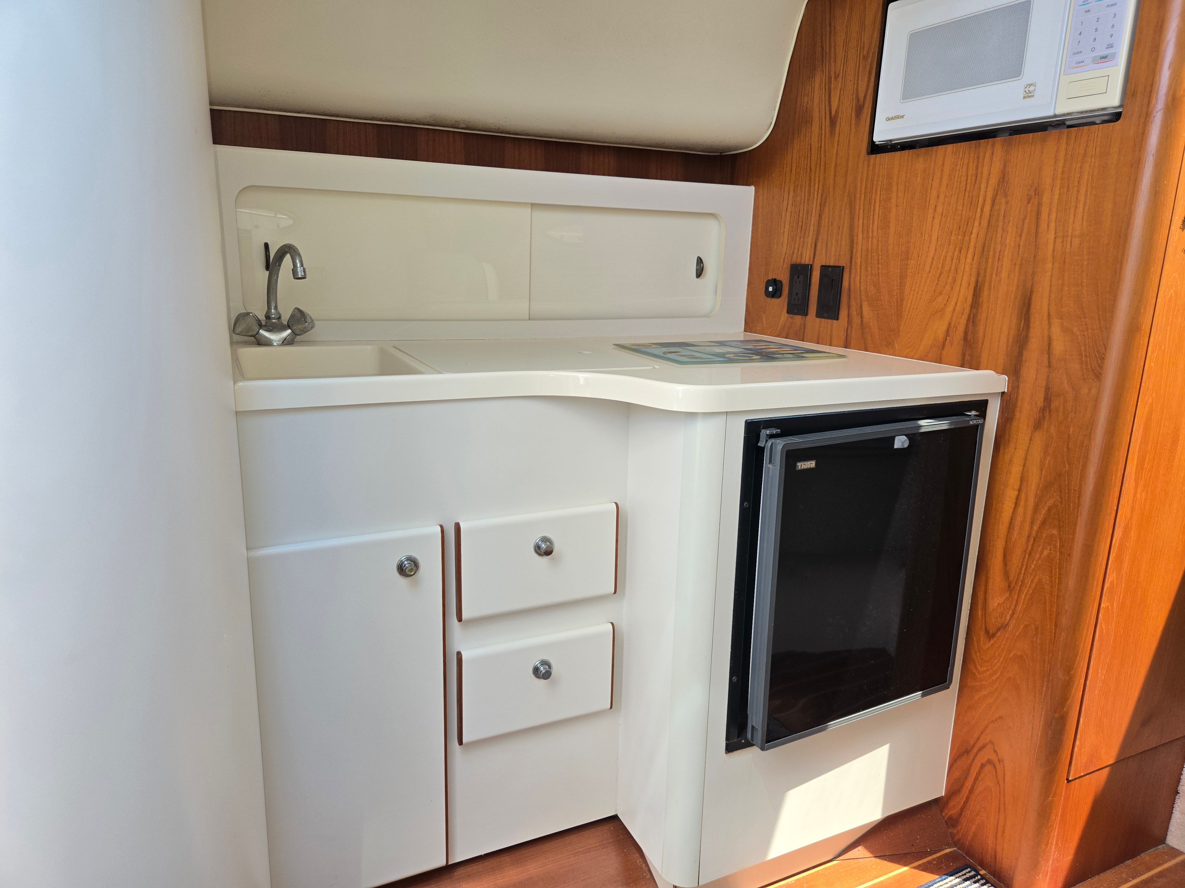 Galley area with sink, refrigerator, and microwave in a yacht.