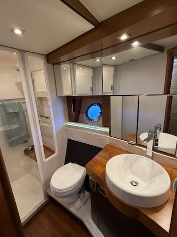 The image shows an elegant yacht bathroom with a sink, toilet, and mirror.