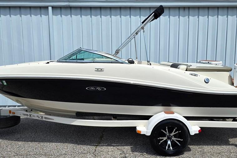 2006 Sea Ray 185 Sport boat on trailer, parked by a metal building.