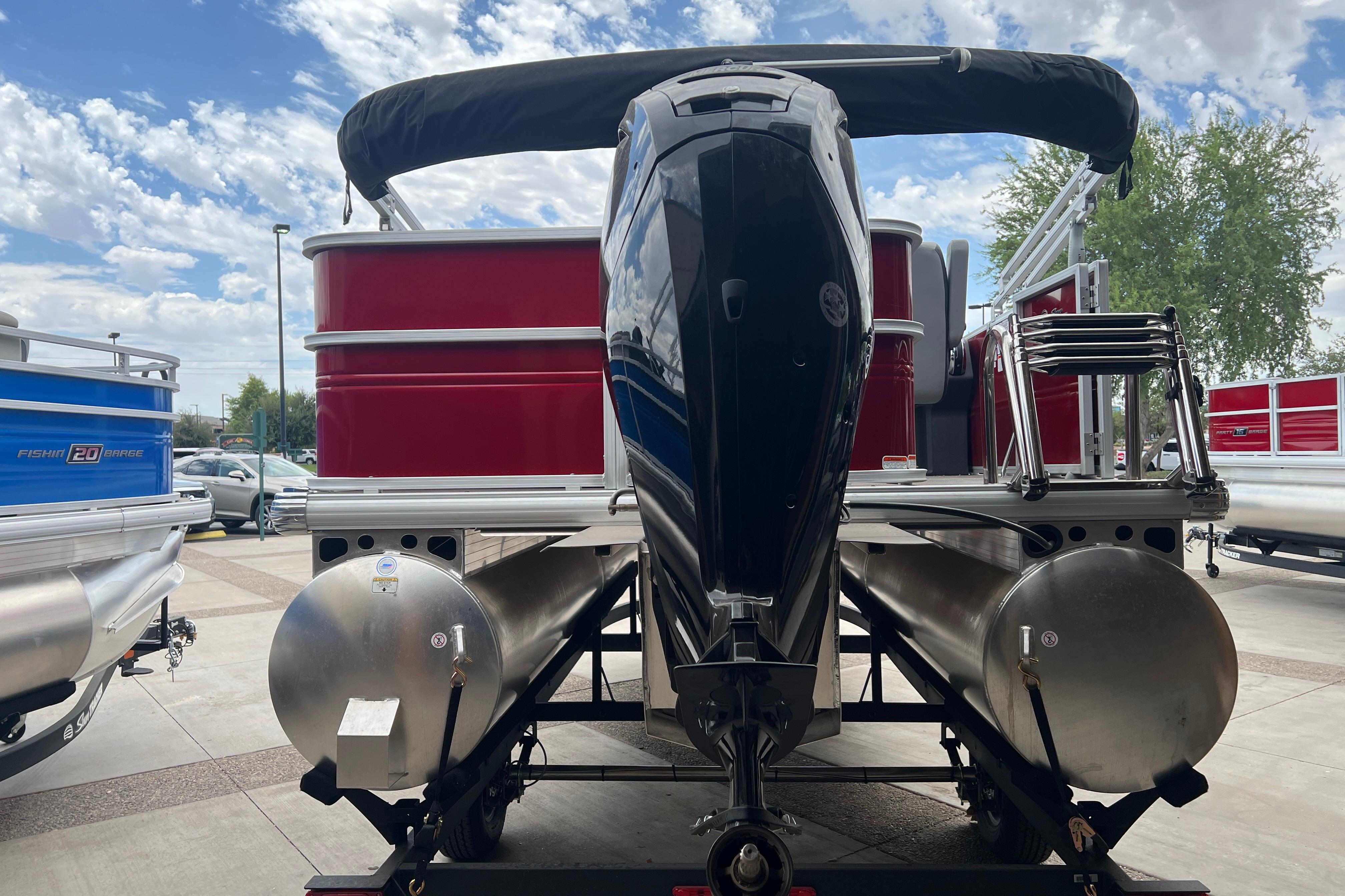 2026 Sun Tracker Party Barge 18 DLX pontoon boat with outboard motor, parked outdoors.