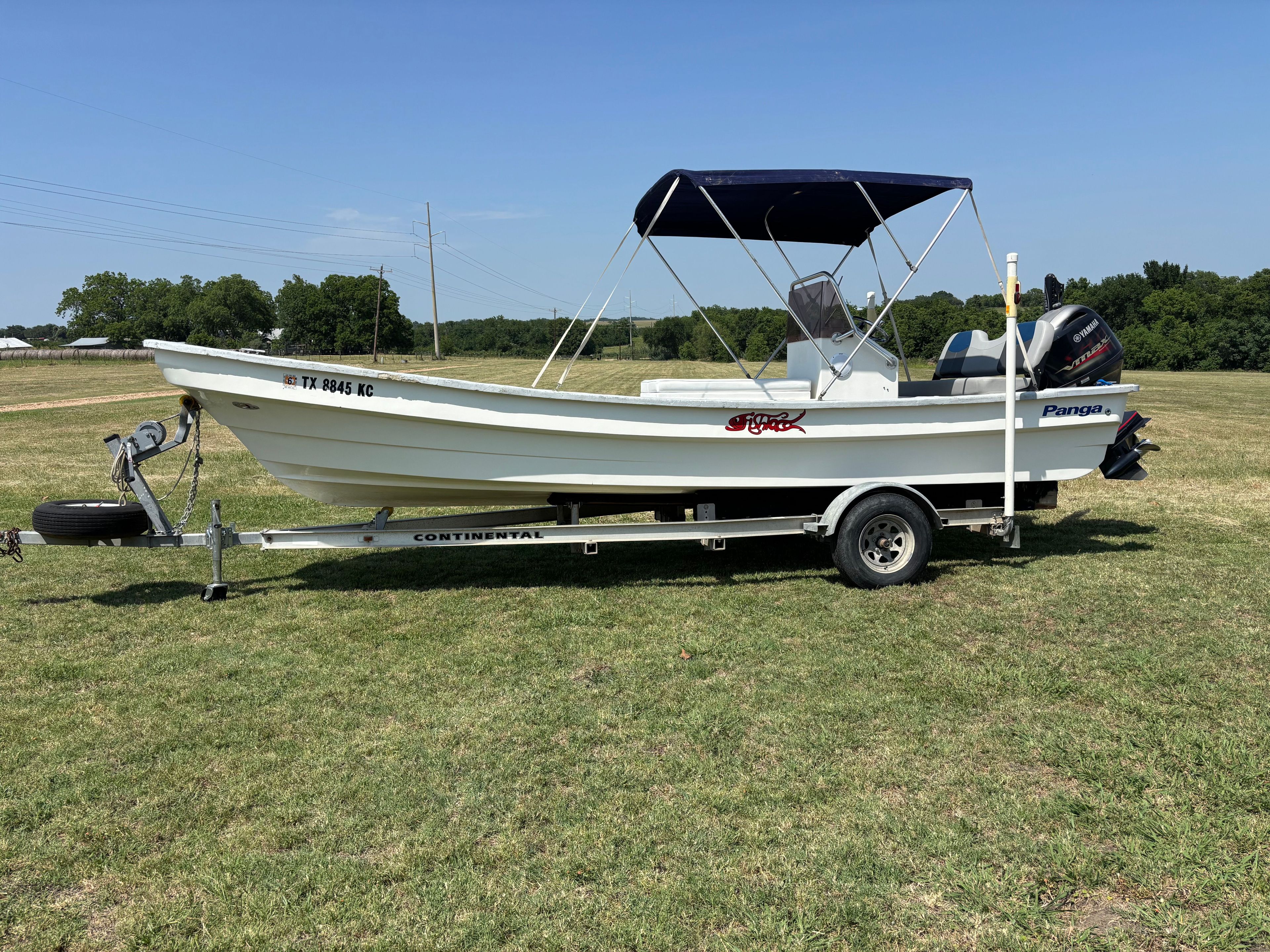 A 2004 Panga Sports 22 boat on a trailer in a grassy field.