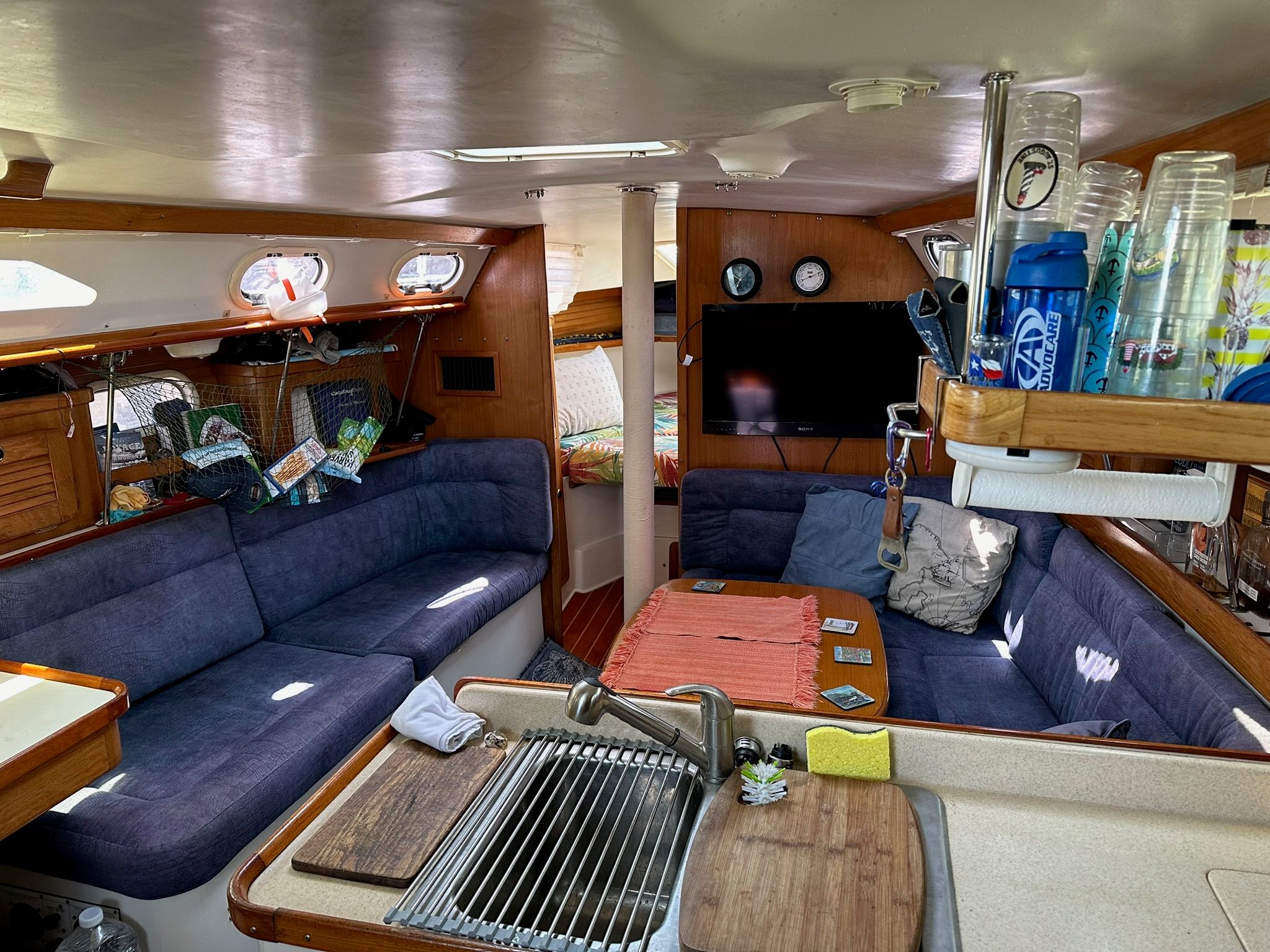 Interior of a Catalina MkII yacht with cozy seating and a small kitchen area.