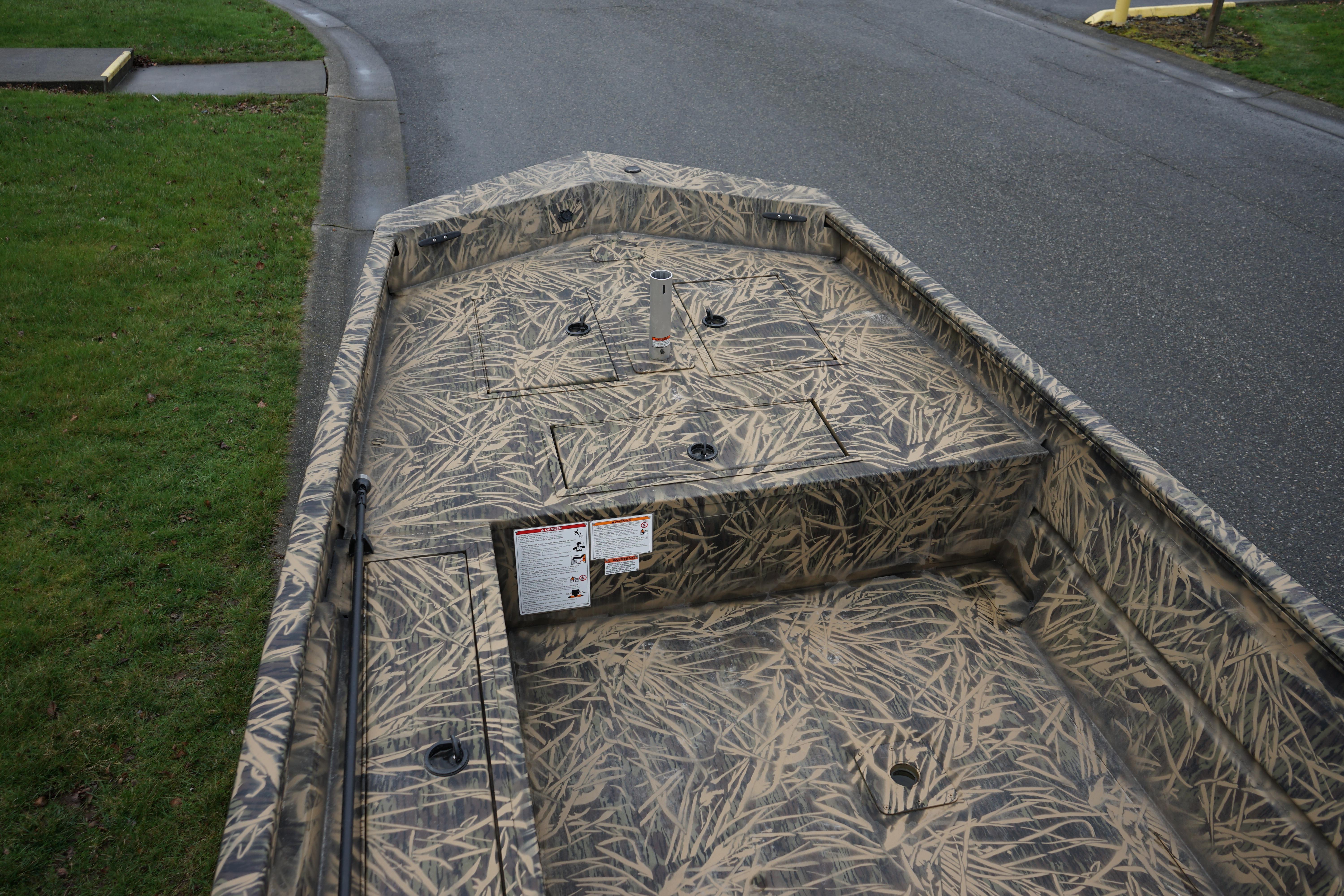 2024 Lund 1760 Predator Tiller boat with camouflage design on a street.