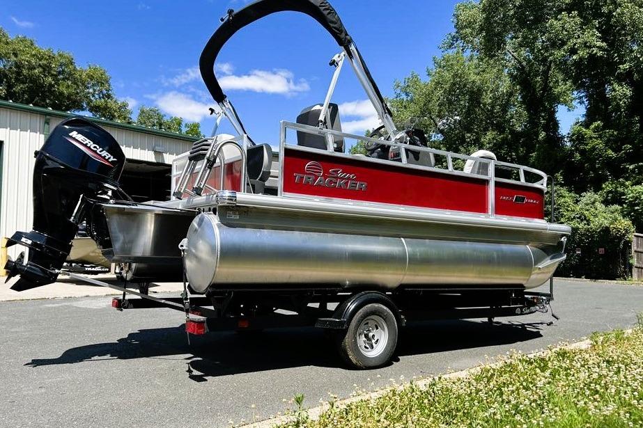 2026 Sun Tracker Bass Buggy 16 XL Select pontoon boat on trailer, outdoors.