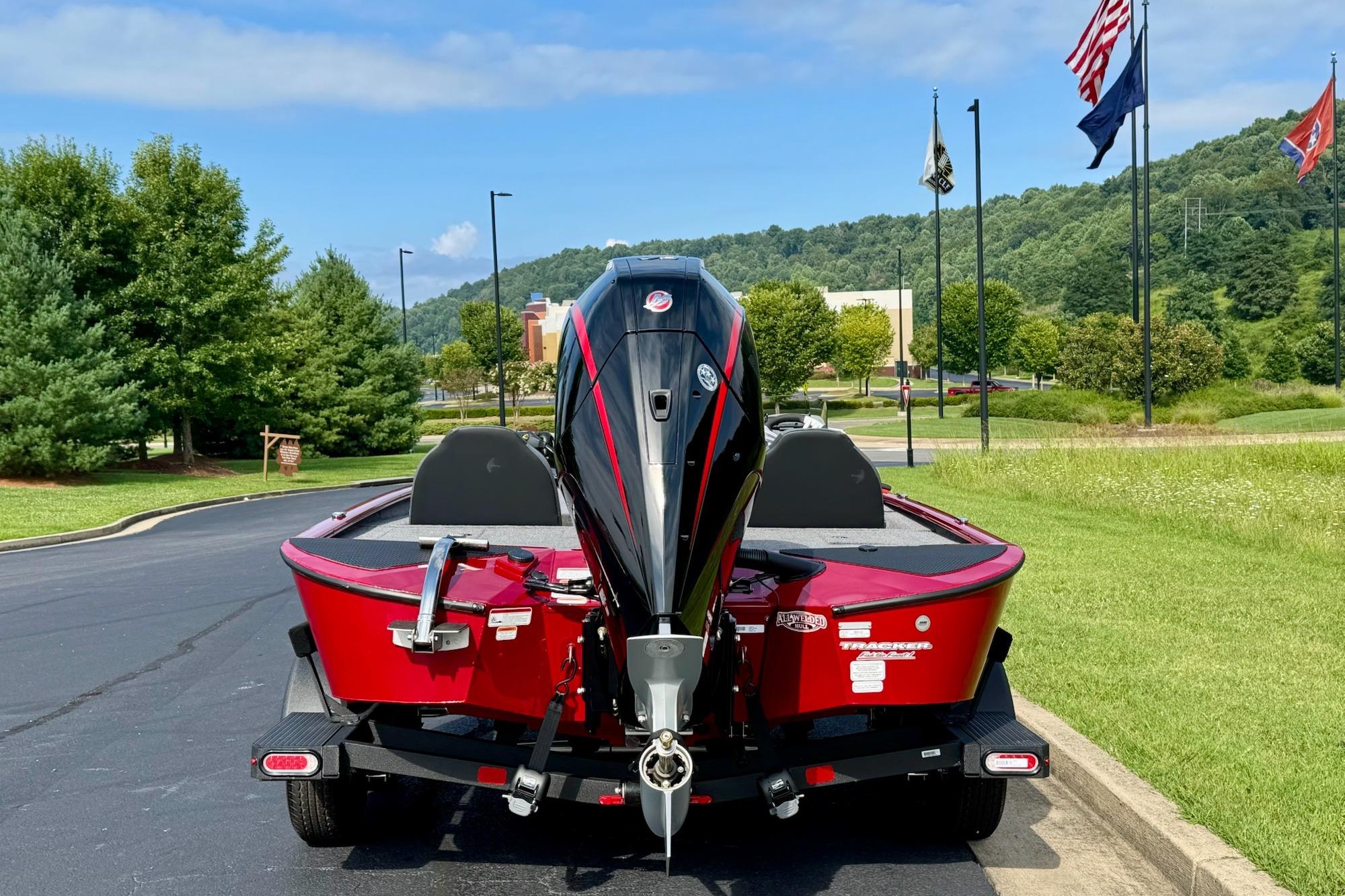 2026 Tracker Savage 215 boat on trailer, parked near flags and greenery.