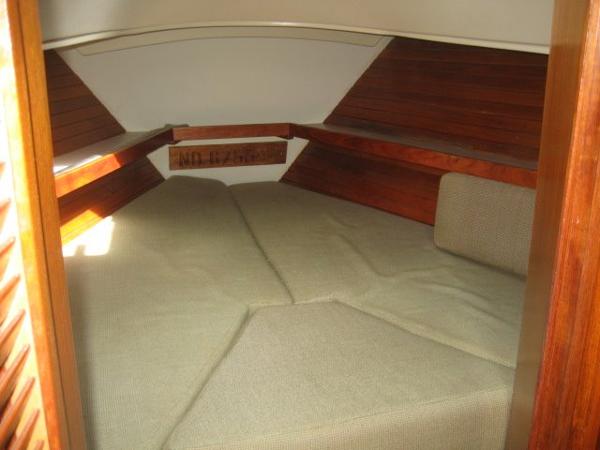Interior of a C&C Landfall yacht with cushioned sleeping area and wooden walls.