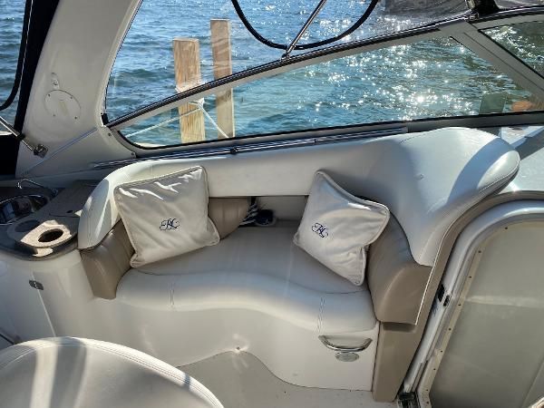Interior of a boat with white seating and cushions, overlooking water in the background.
