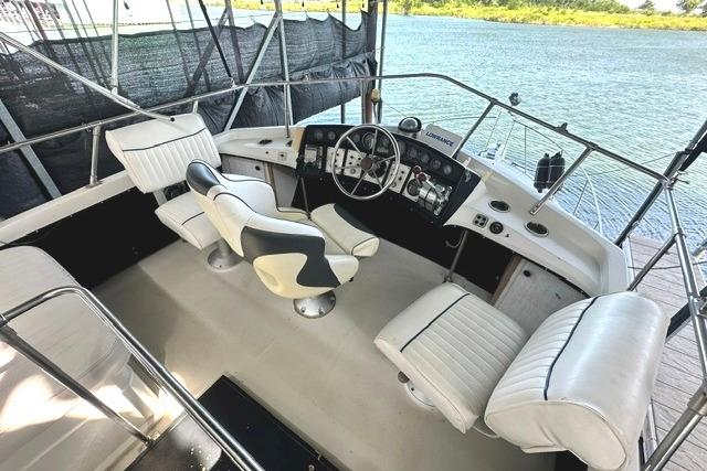 1989 Carver 32 Aft Cabin Motor Yacht cockpit with white seating and steering controls.