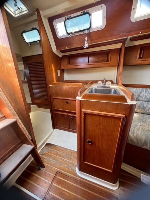 Interior of a 1988 Pearson 28 sailboat with wood finish and a sink.