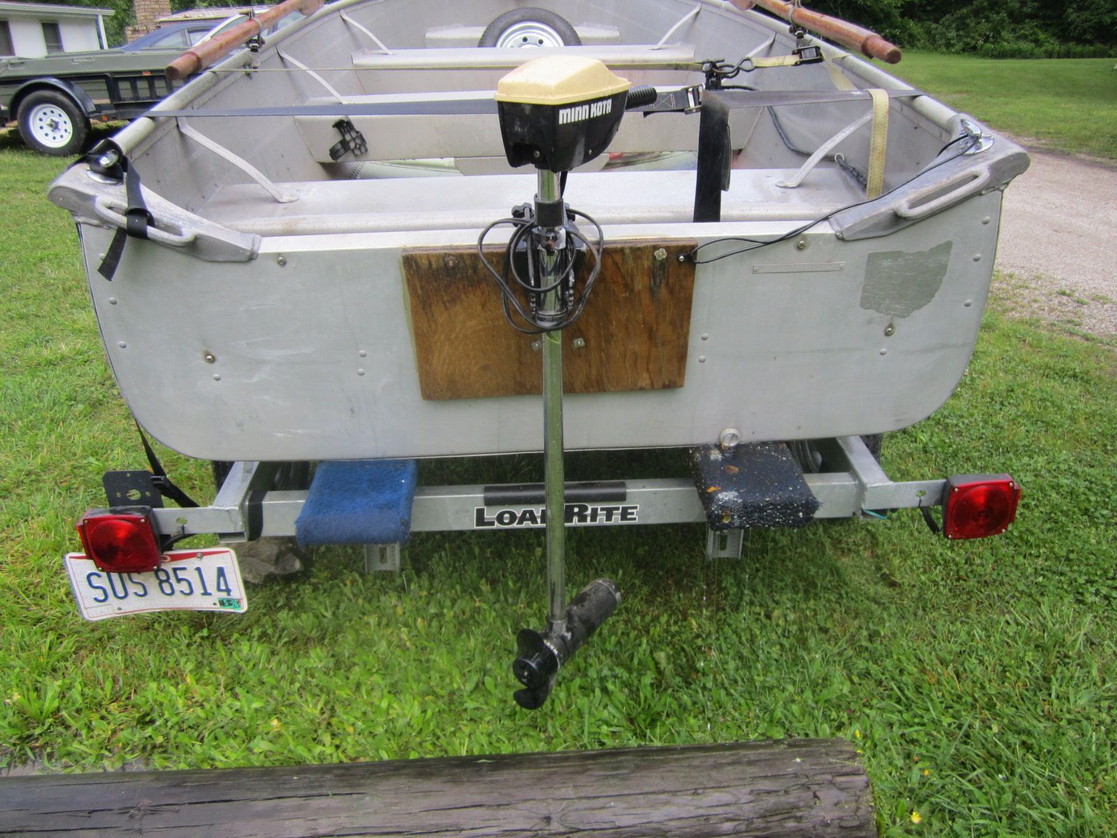 A small boat on a trailer with an outboard motor.