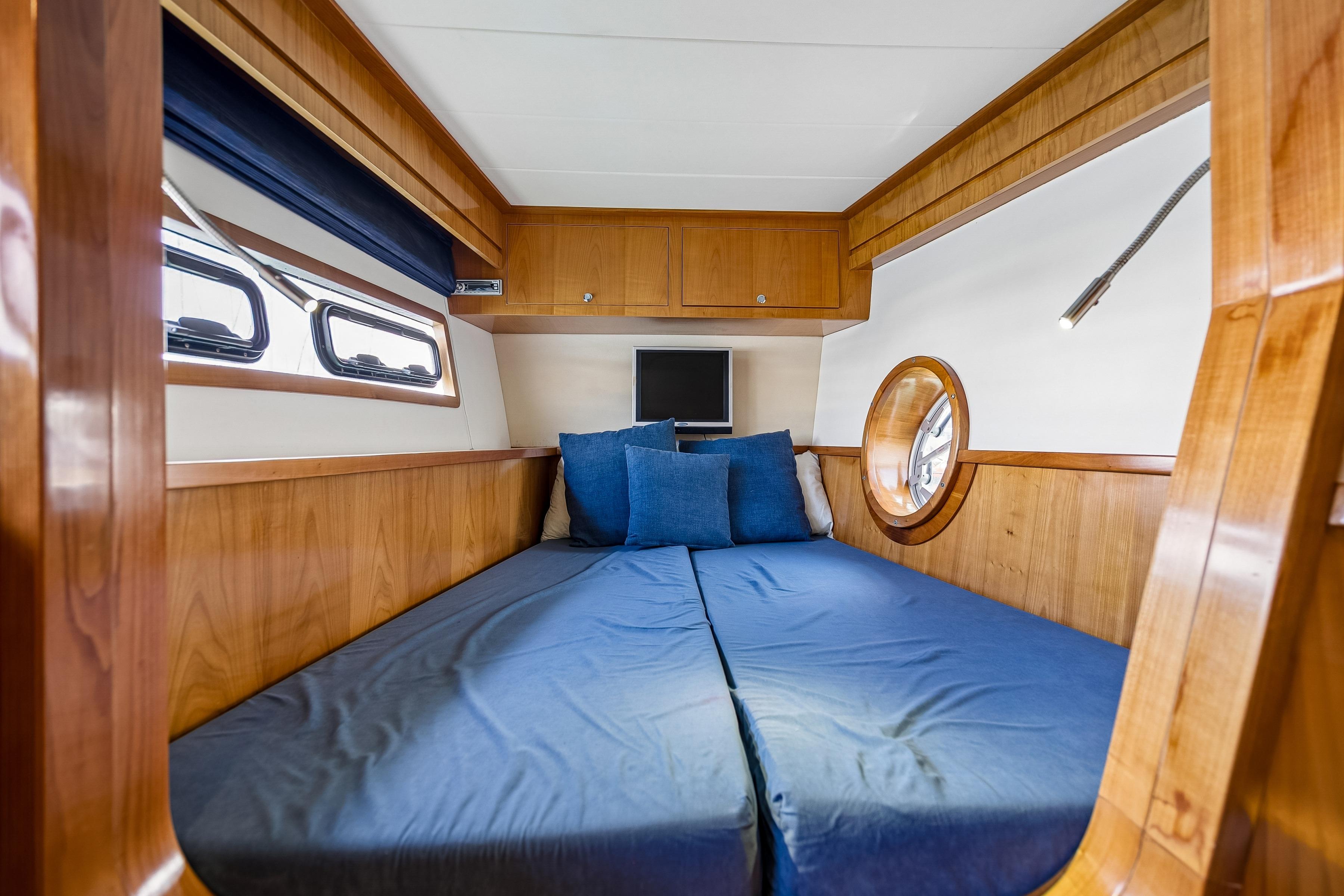 Luxurious cabin interior of 2009 Catana 65 yacht with wooden finish and cozy bedding.