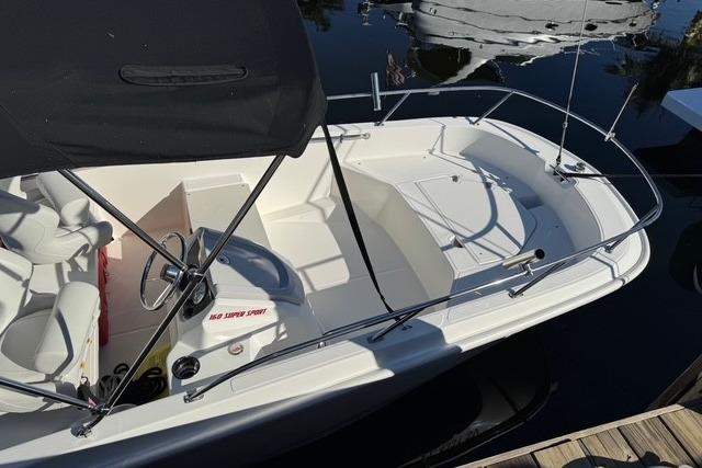 2024 Boston Whaler 160 SS boat with canopy, docked on calm water.