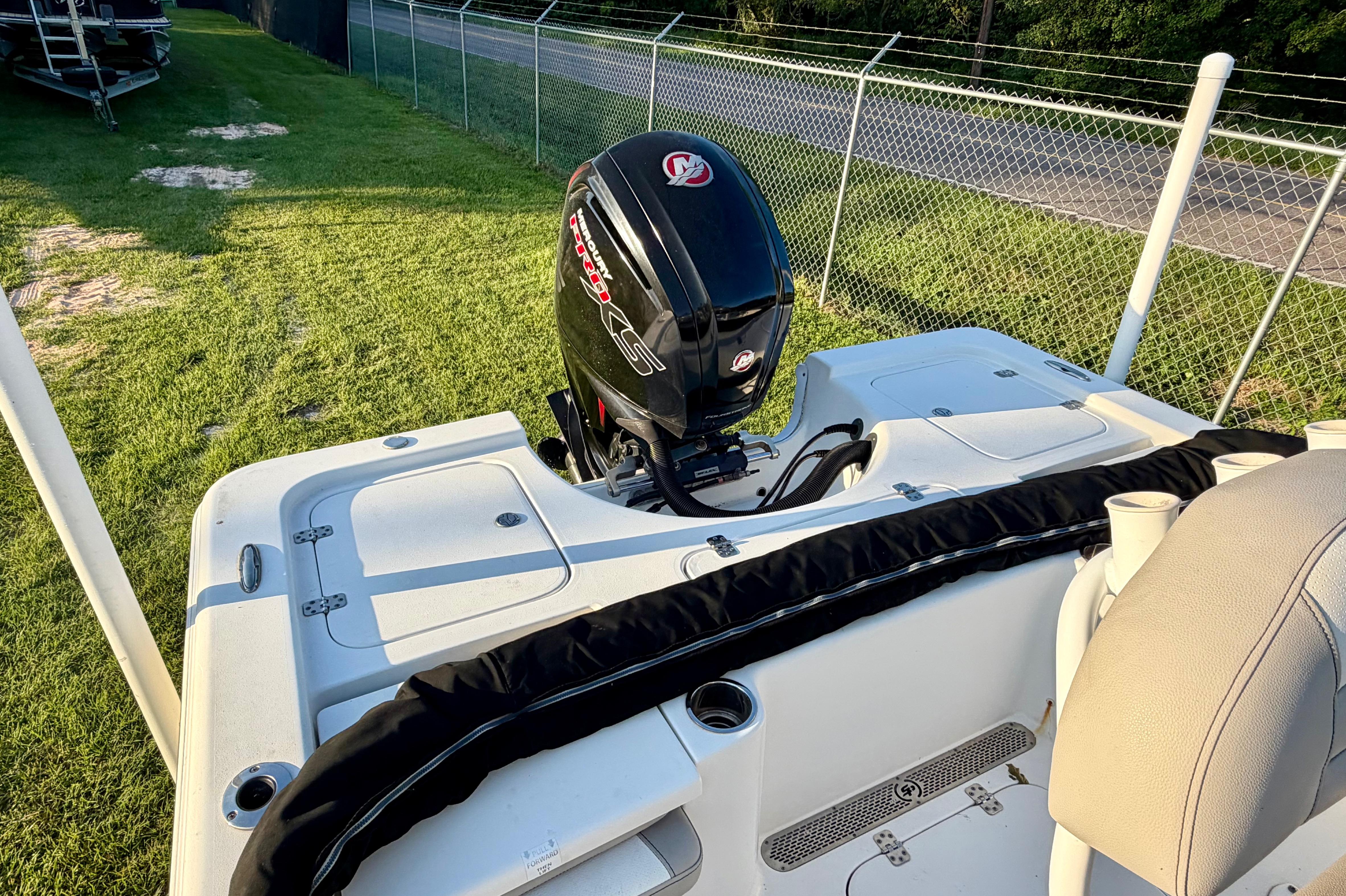 2018 Sea Pro 208 Bay boat with powerful outboard motor, parked on grass near a fence.