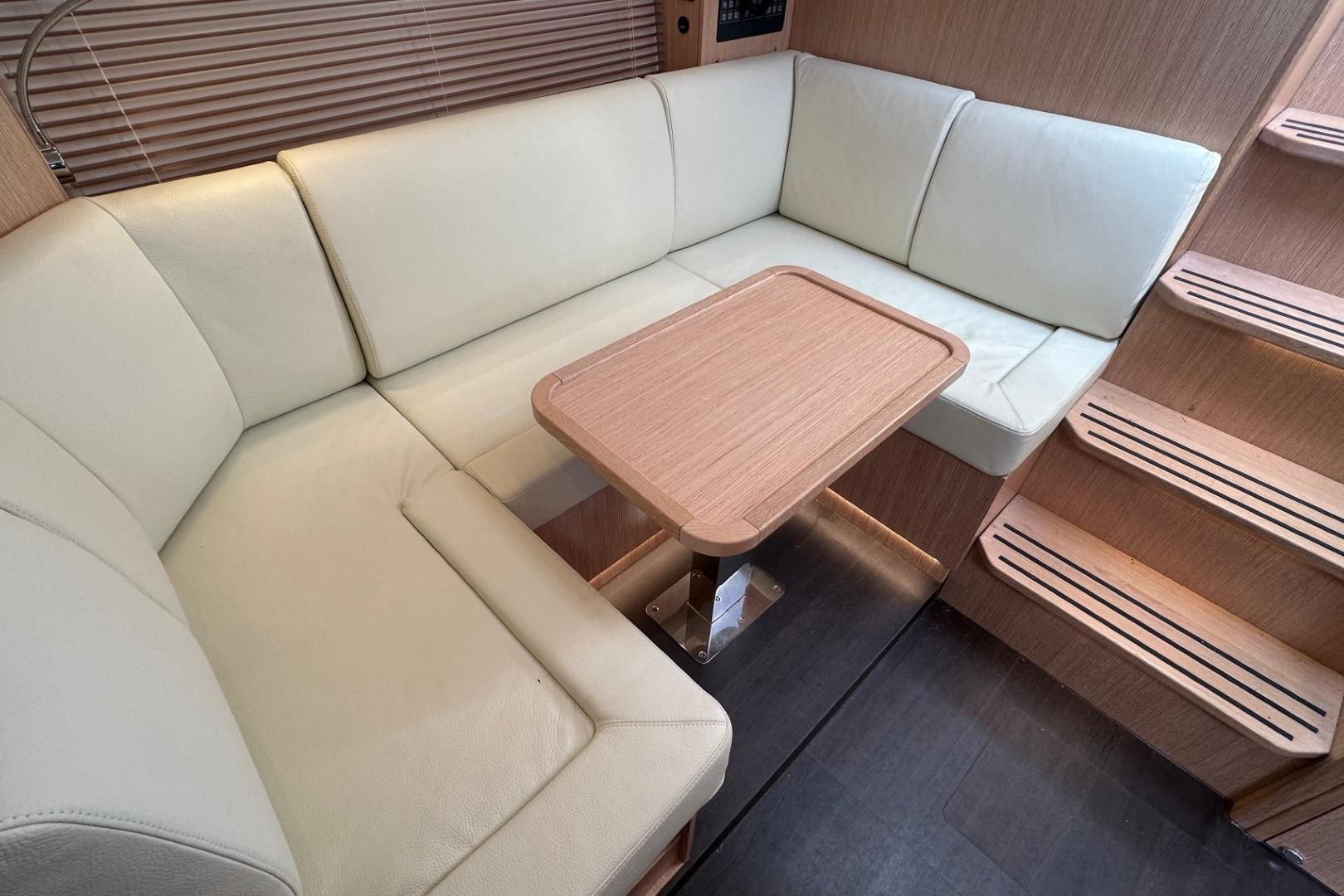 Luxurious interior of 2023 Bavaria SR41 yacht with cream seating and wooden table.