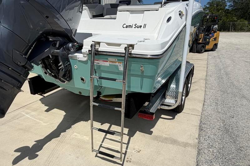 2026 Hurricane SunDeck Sport 2050 OB boat with ladder and outboard motor.