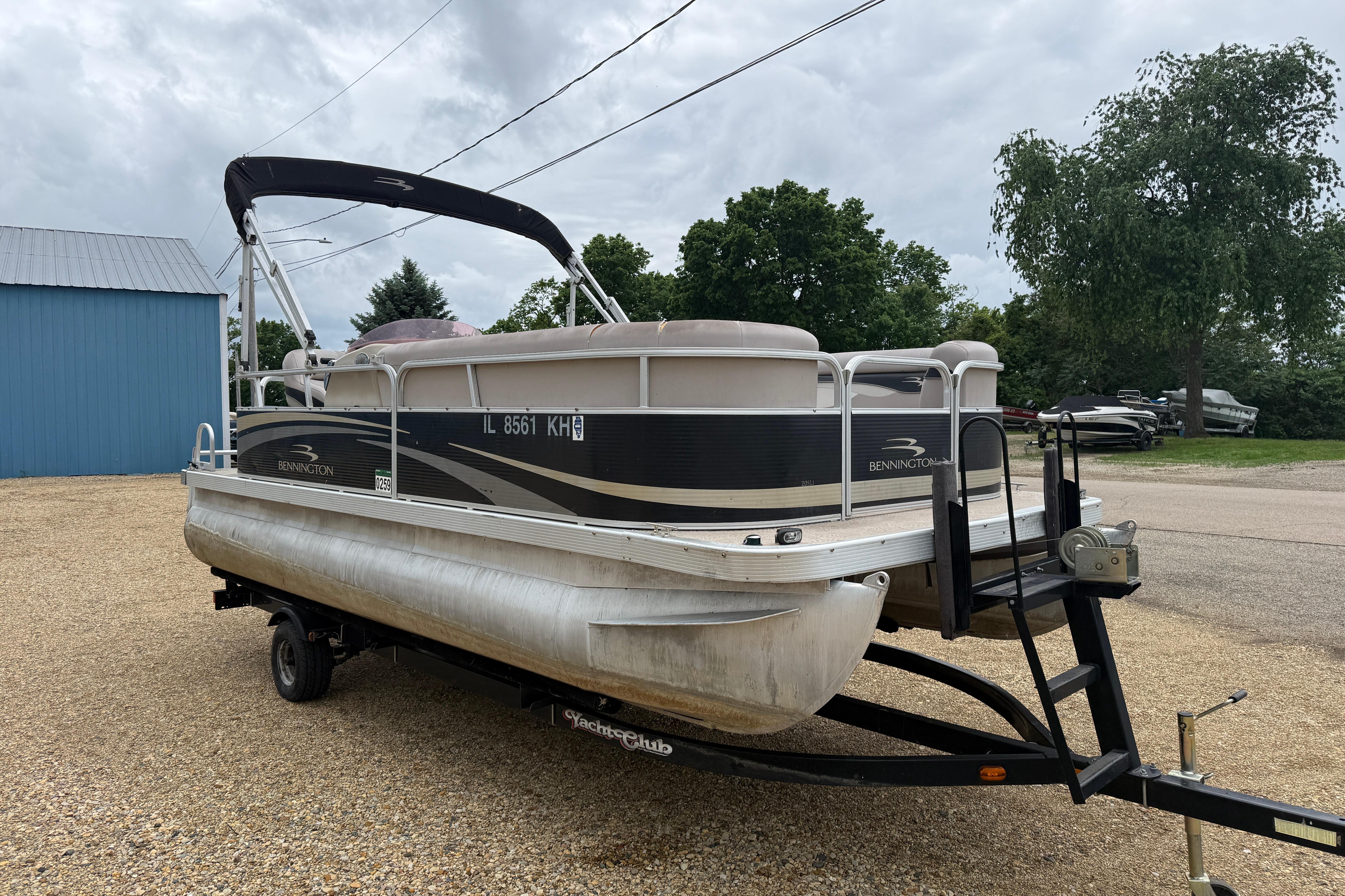 2010 Bennington 20SLi pontoon boat on trailer, parked outdoors near blue building.