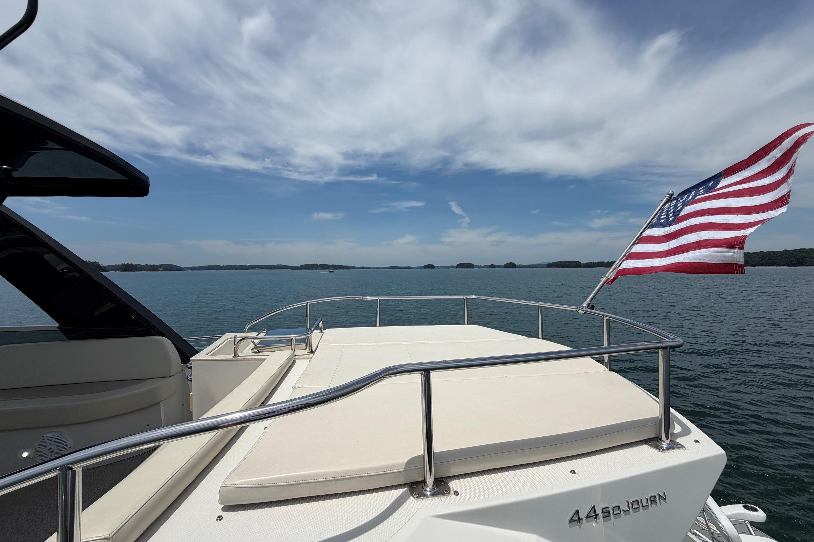 2011 Carver 44 Sojourn yacht with American flag on open water under blue sky.