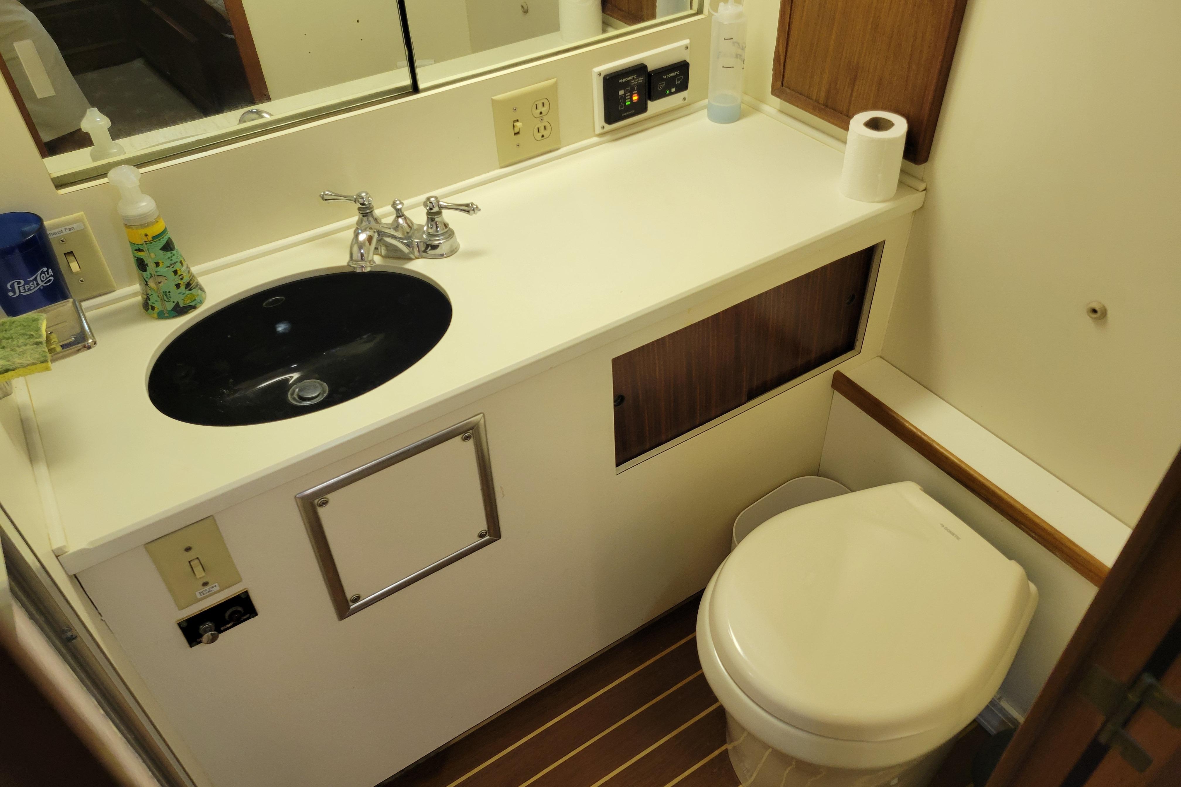 1980 Hatteras 53 Yacht Fisherman bathroom with sink, toilet, and wooden accents.