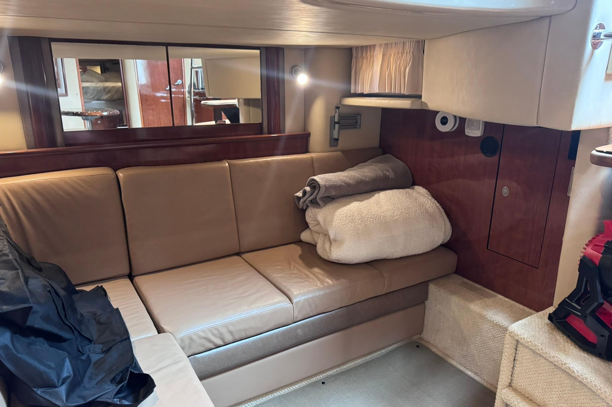 Interior of 2004 Sea Ray 390 Sundancer yacht with beige leather seating and cozy blankets.