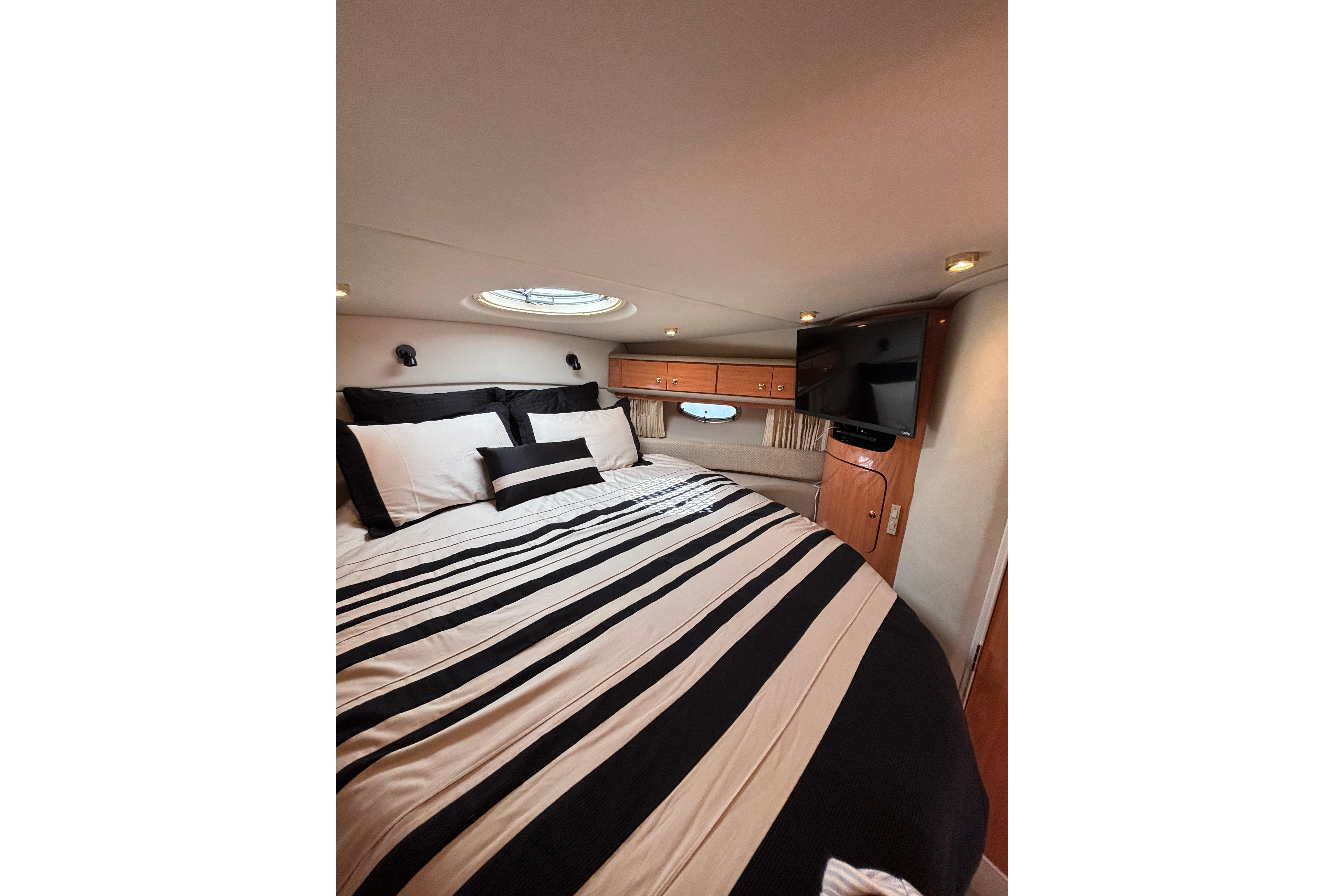 Luxurious cabin interior of 2000 Regal Commodore 4160 yacht with striped bedding.