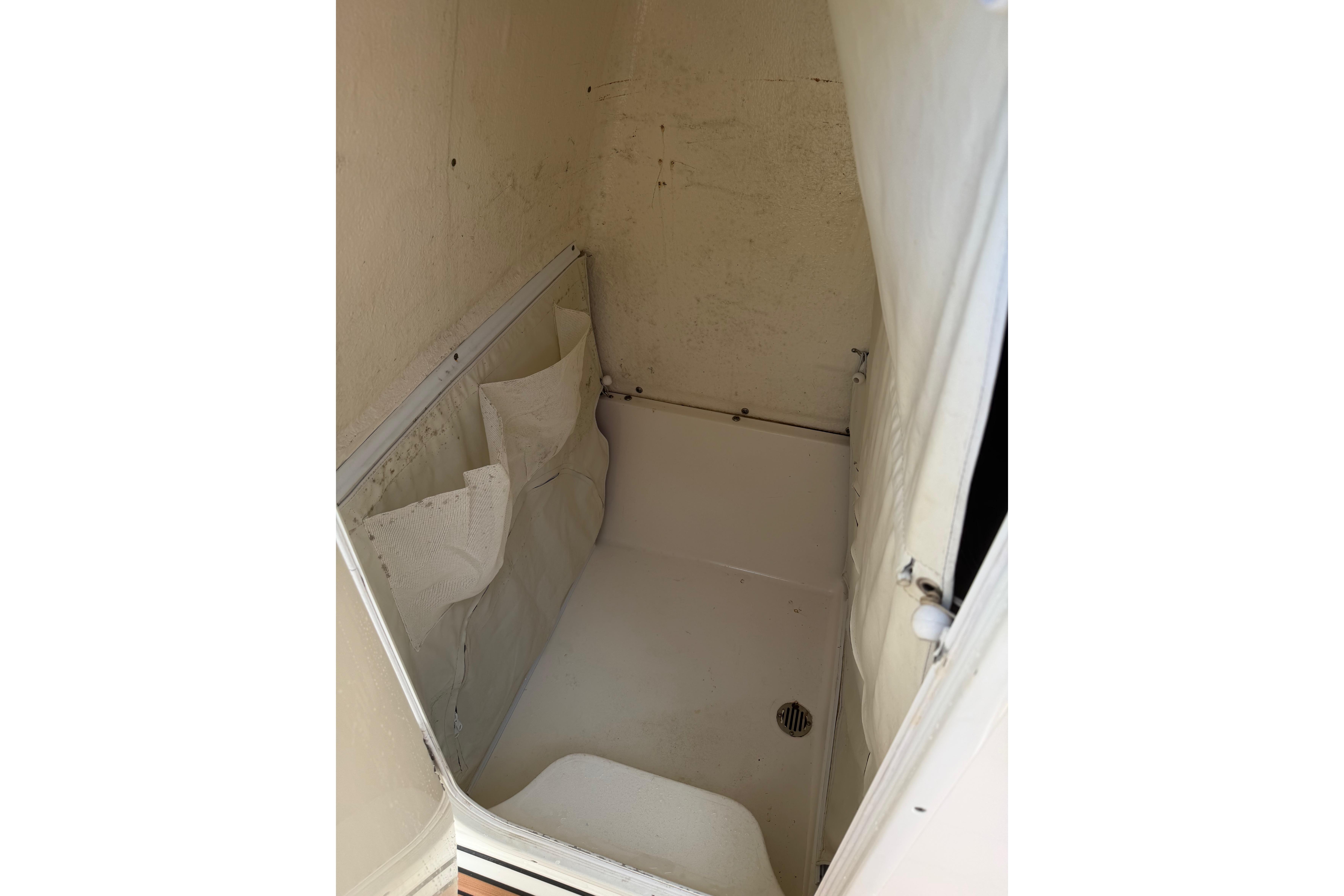 Interior storage compartment of 2019 Key West 263 FS boat, featuring white walls and drain.