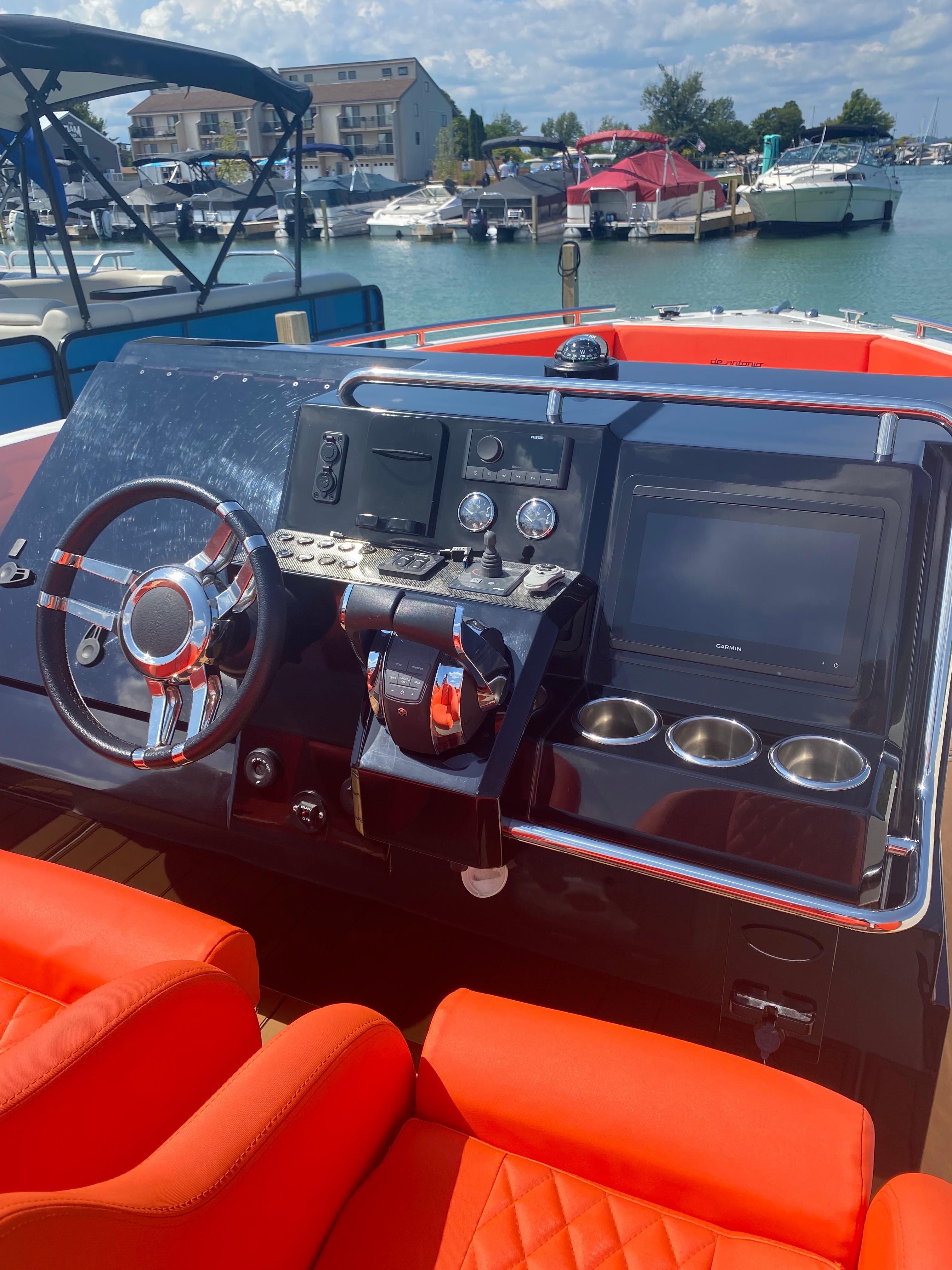 Helm of 2020 De Antonio Yachts D28 with modern controls and vibrant orange seating.
