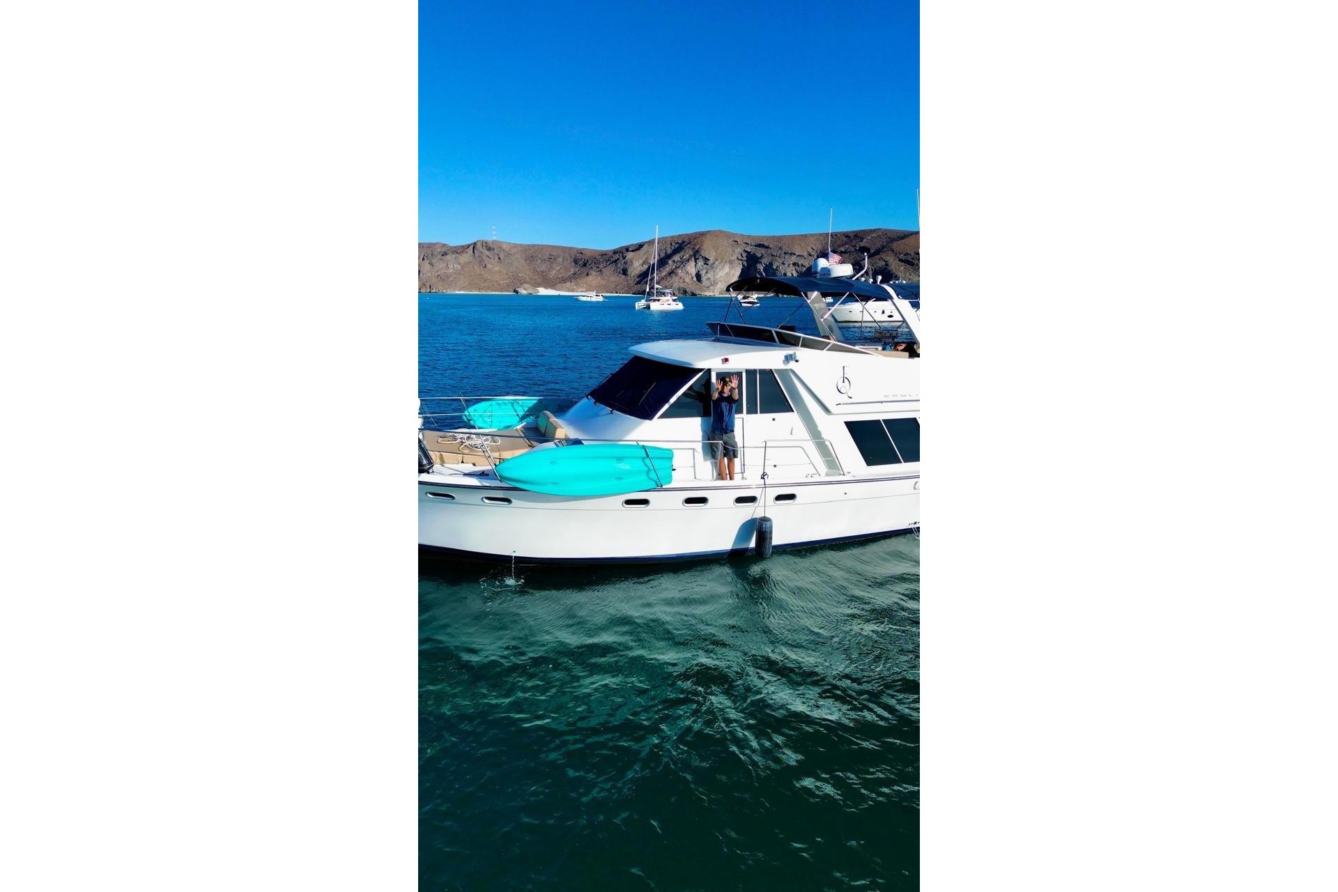 2000 Bayliner 4788 Pilot House Motoryacht anchored in scenic bay with kayaks on deck.