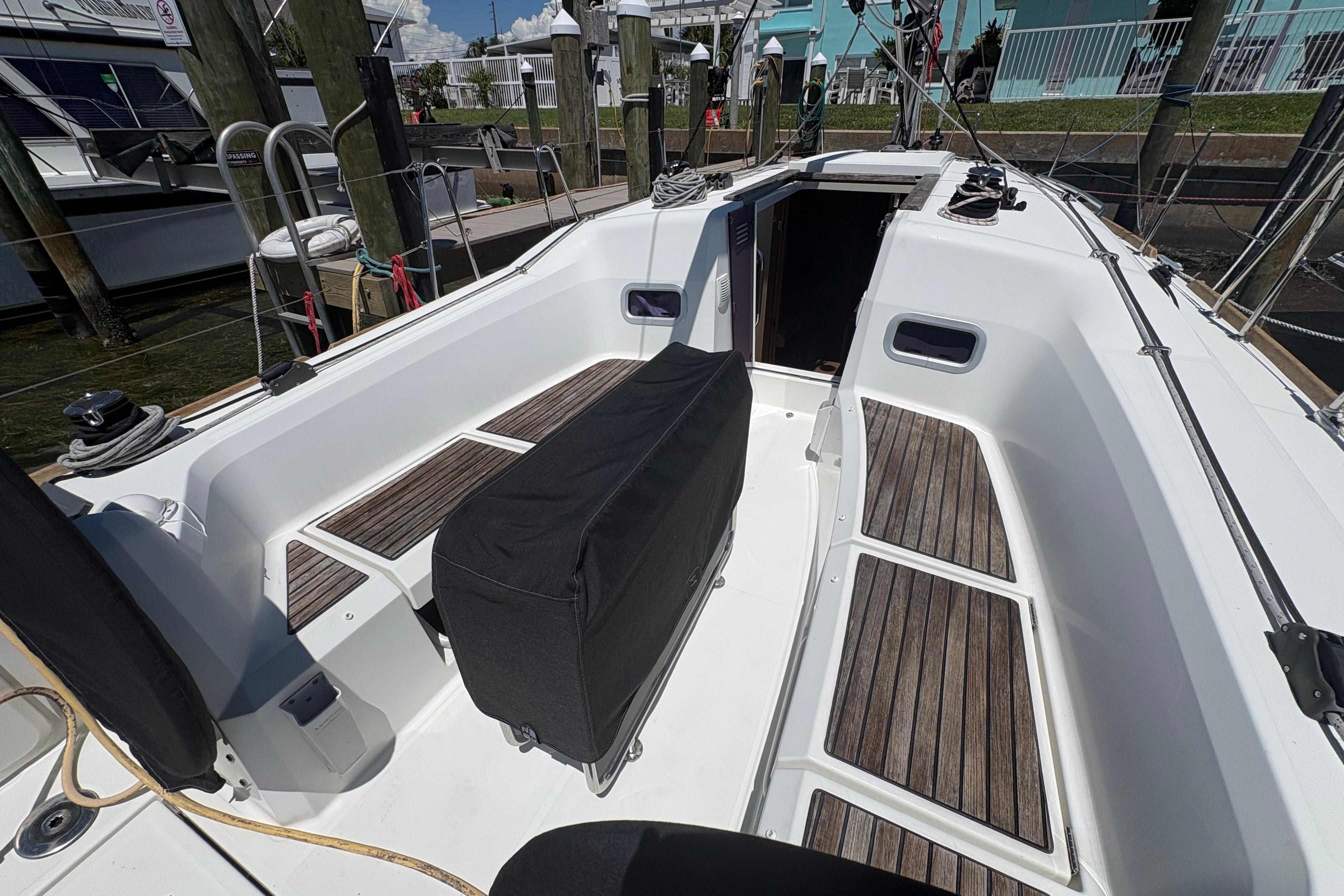 Cockpit of 2021 Jeanneau Sun Odyssey 349 sailboat with wooden flooring and covered equipment.