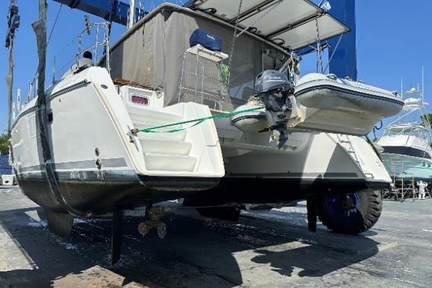 2010 Lagoon 421 catamaran on dry dock with attached dinghy and visible propeller.