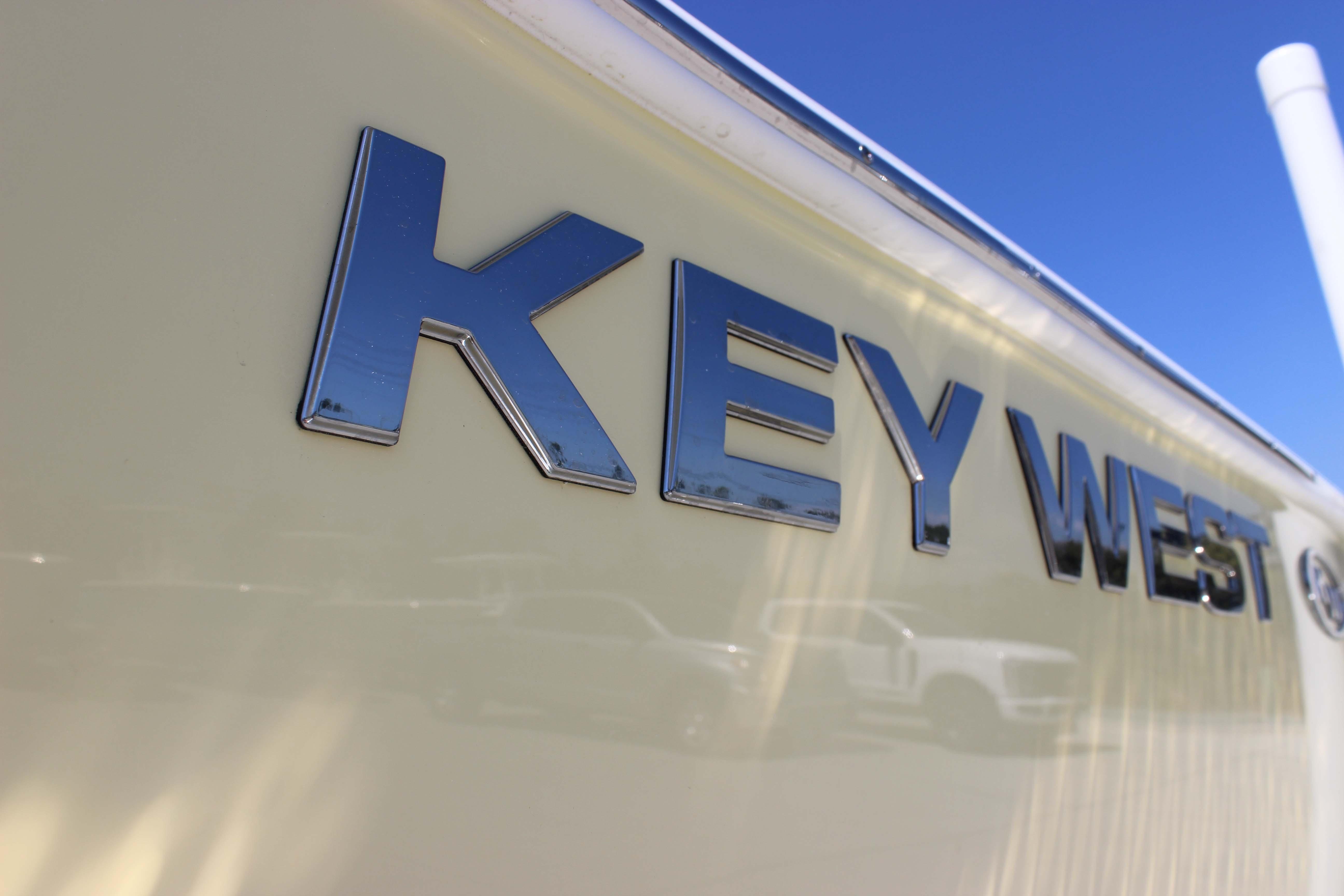 Key West 203 FS 2026 boat logo on a sleek, cream-colored hull under clear blue sky.
