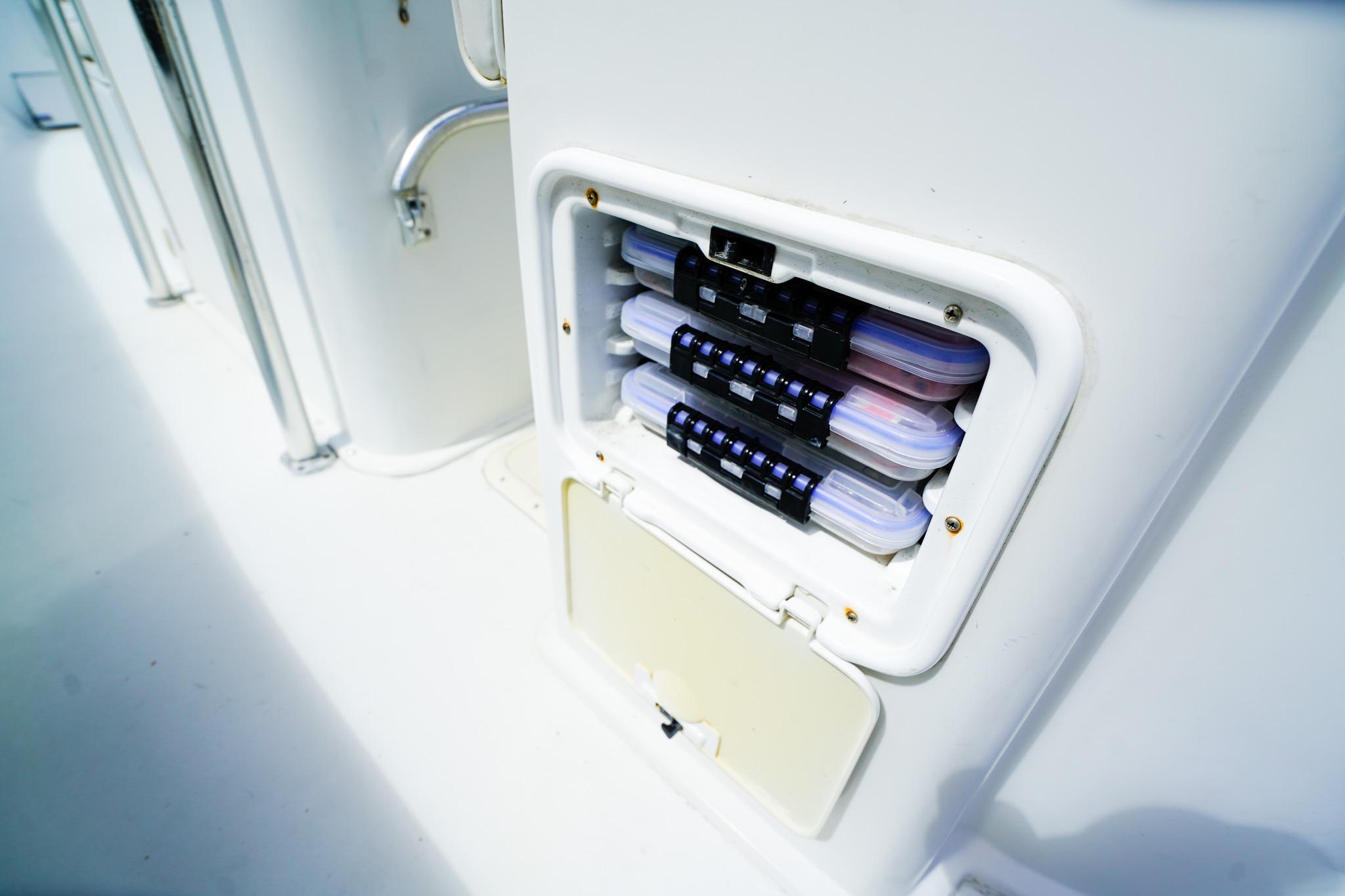 Storage compartment on a 1977 Scarborough 27 CC boat, containing organized tackle boxes.