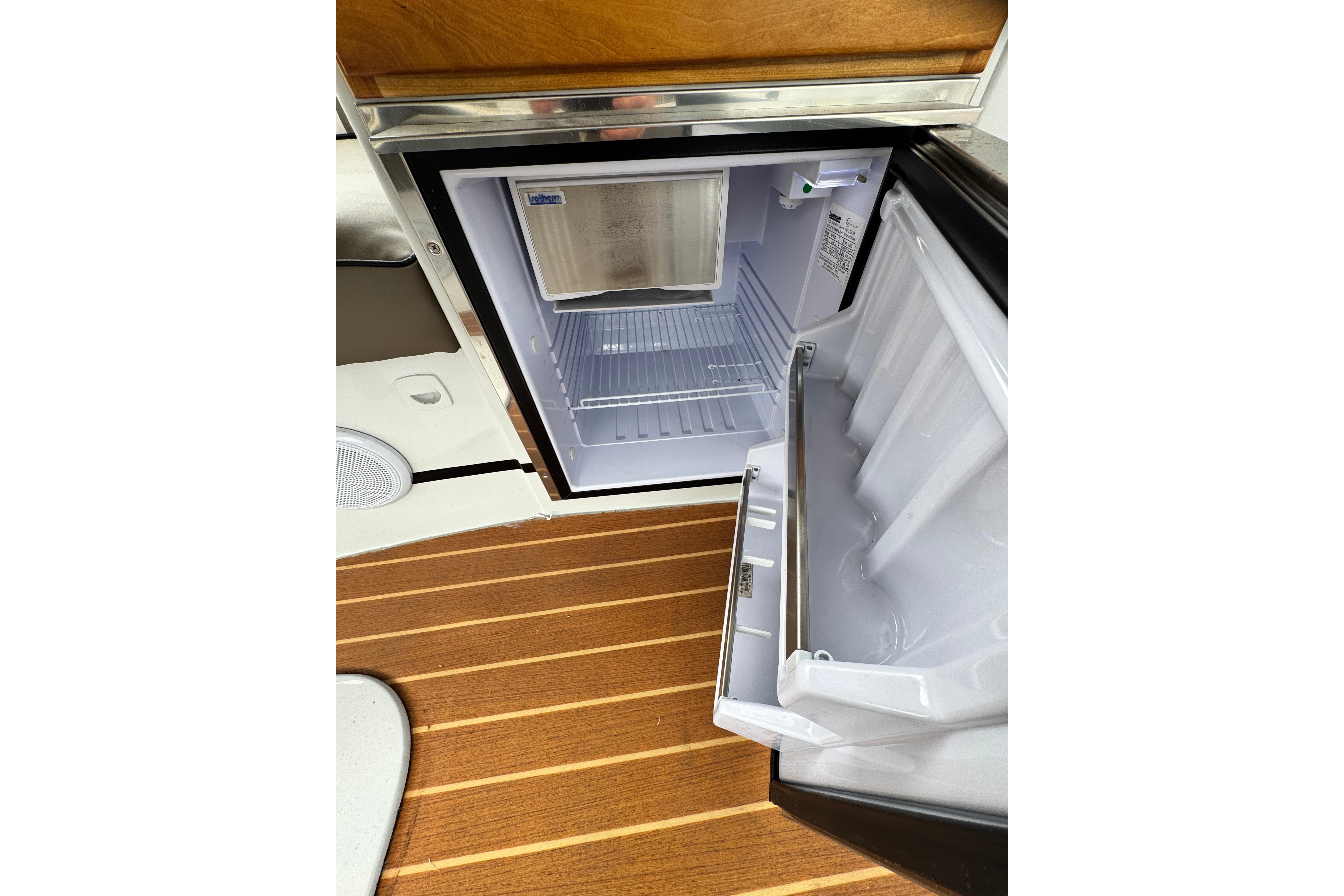 Open refrigerator on 2023 Duffy bay cruiser, showcasing interior and wooden flooring.