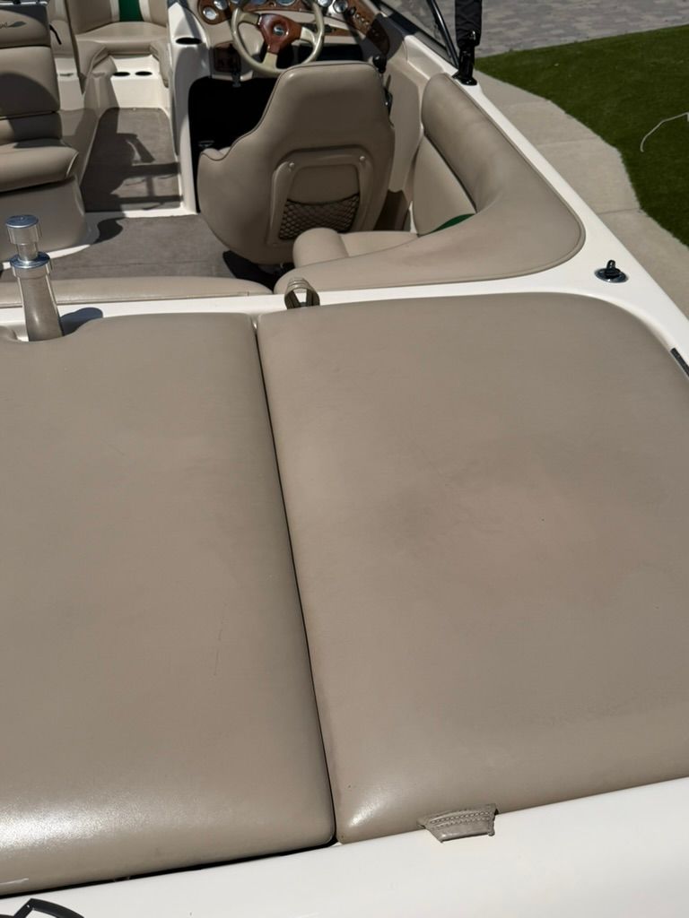 Interior view of a boat with beige upholstery and a steering wheel.