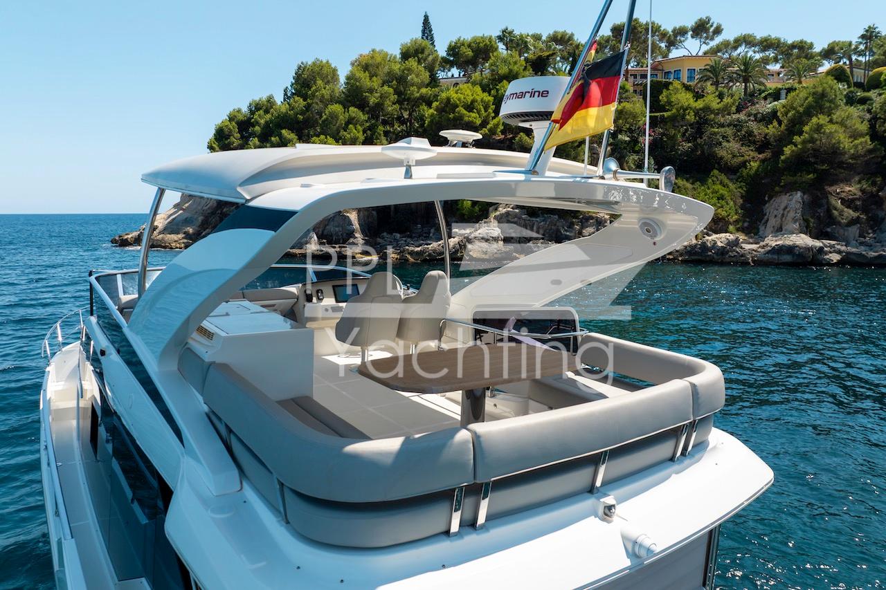 Luxury Absolute 47 Fly yacht, 2021 model, cruising near scenic coastline with lush greenery.