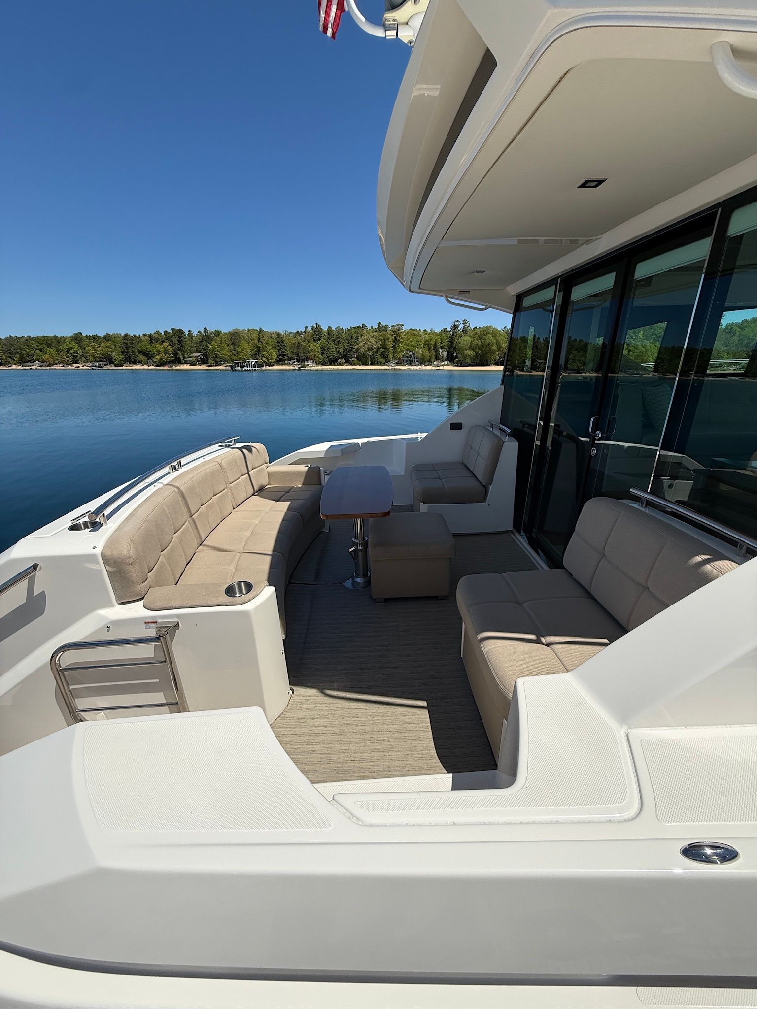 The image shows the stern of a 2017 Tiara Yachts C44 Coupe with beige seating and a table.