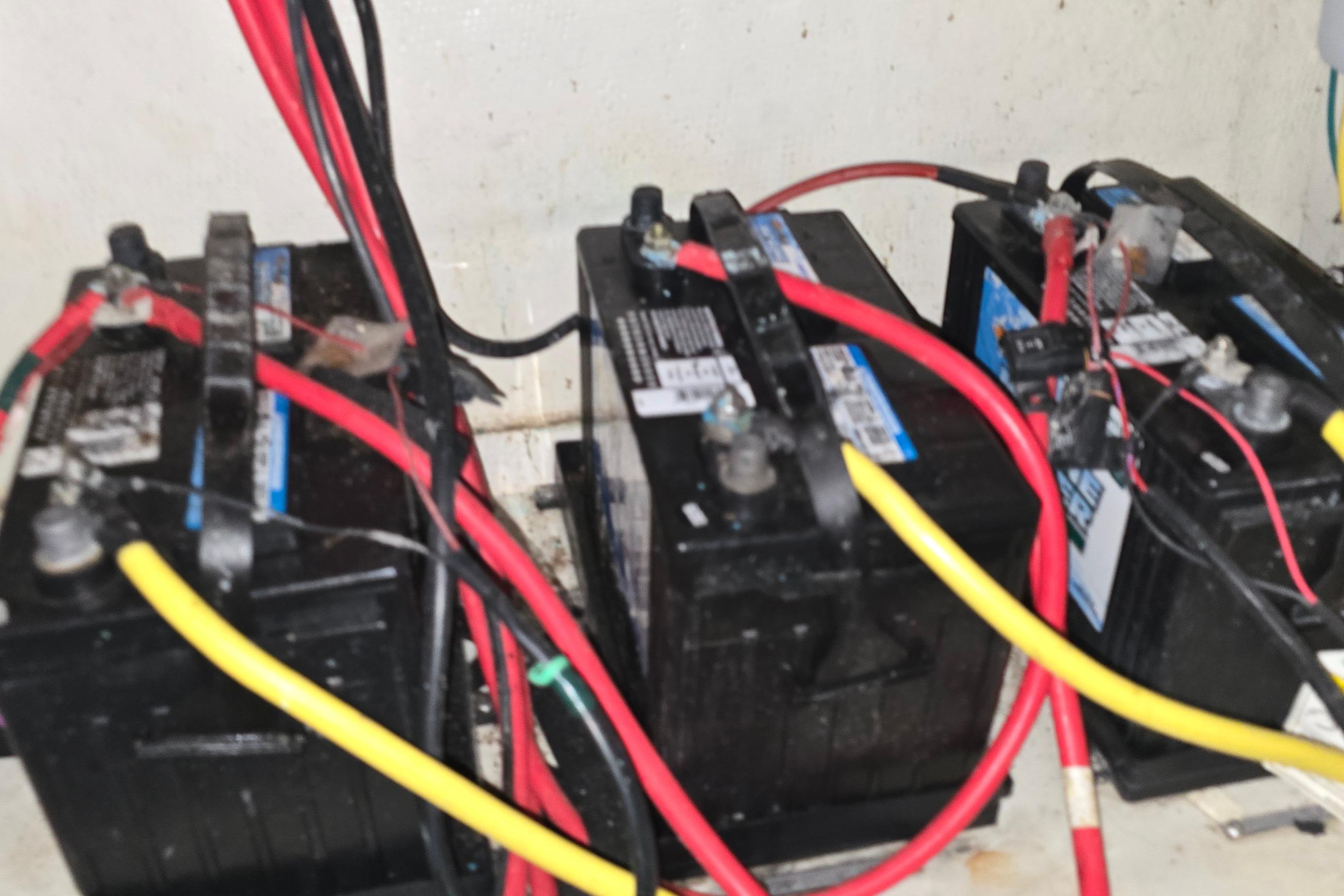 Three marine batteries with red and yellow cables in a 2018 Four Winns V355 boat.