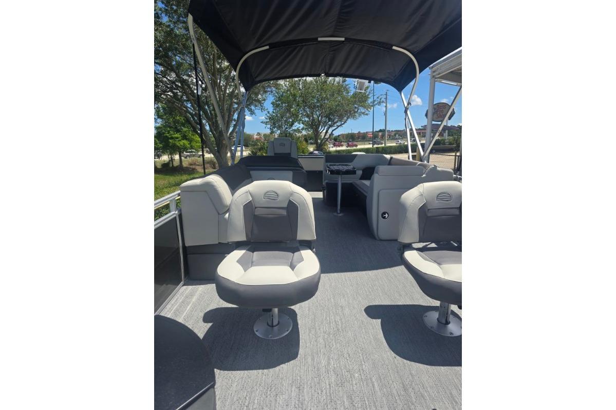 2026 Sun Tracker Fishin' Barge 22 DLX interior with seating and canopy, outdoor setting.