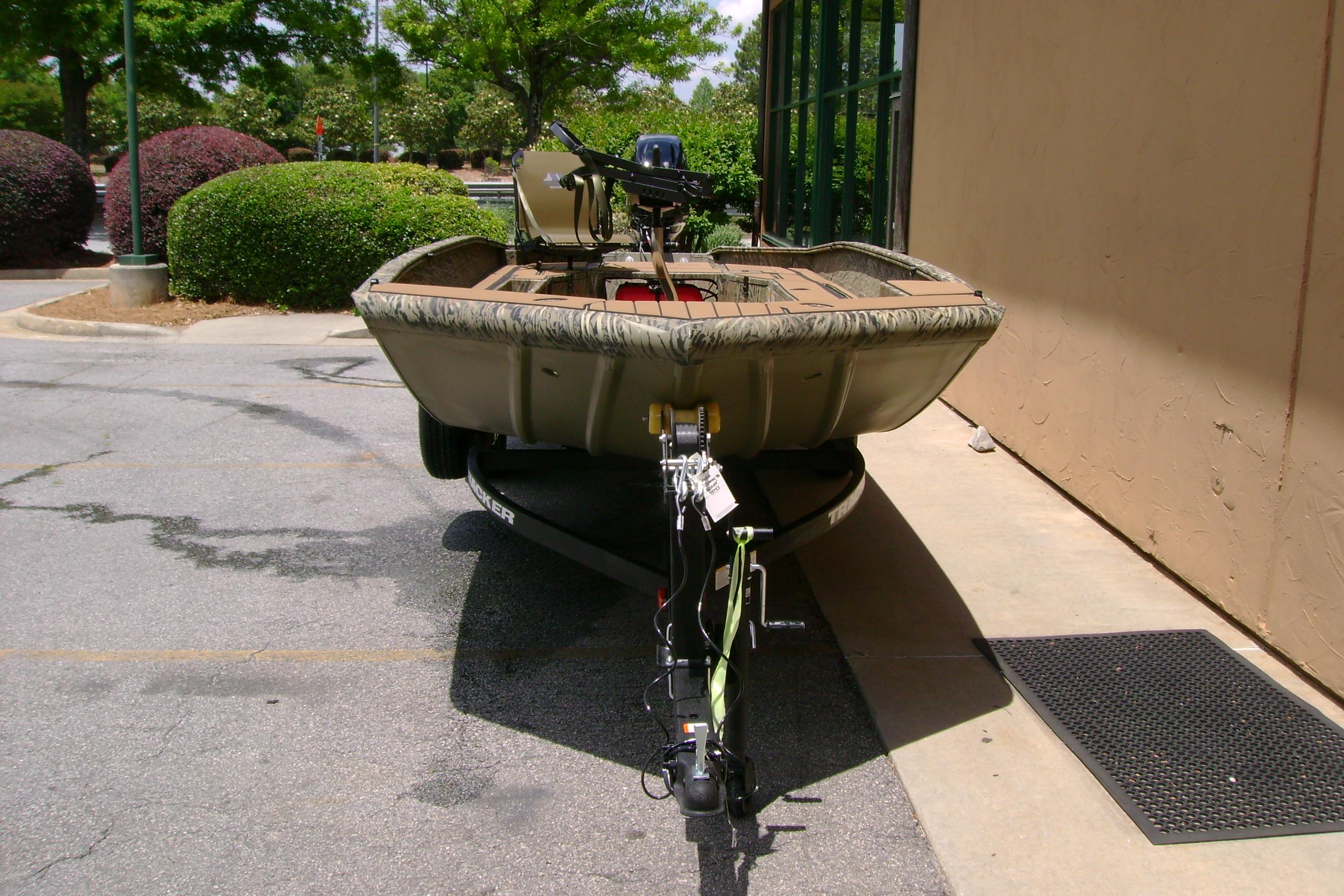 2026 Tracker Grizzly 1756 T Marsh boat on trailer, parked outdoors near greenery.
