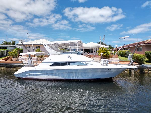 1992 Sea Ray 350 Express Bridge yacht docked by waterfront homes.