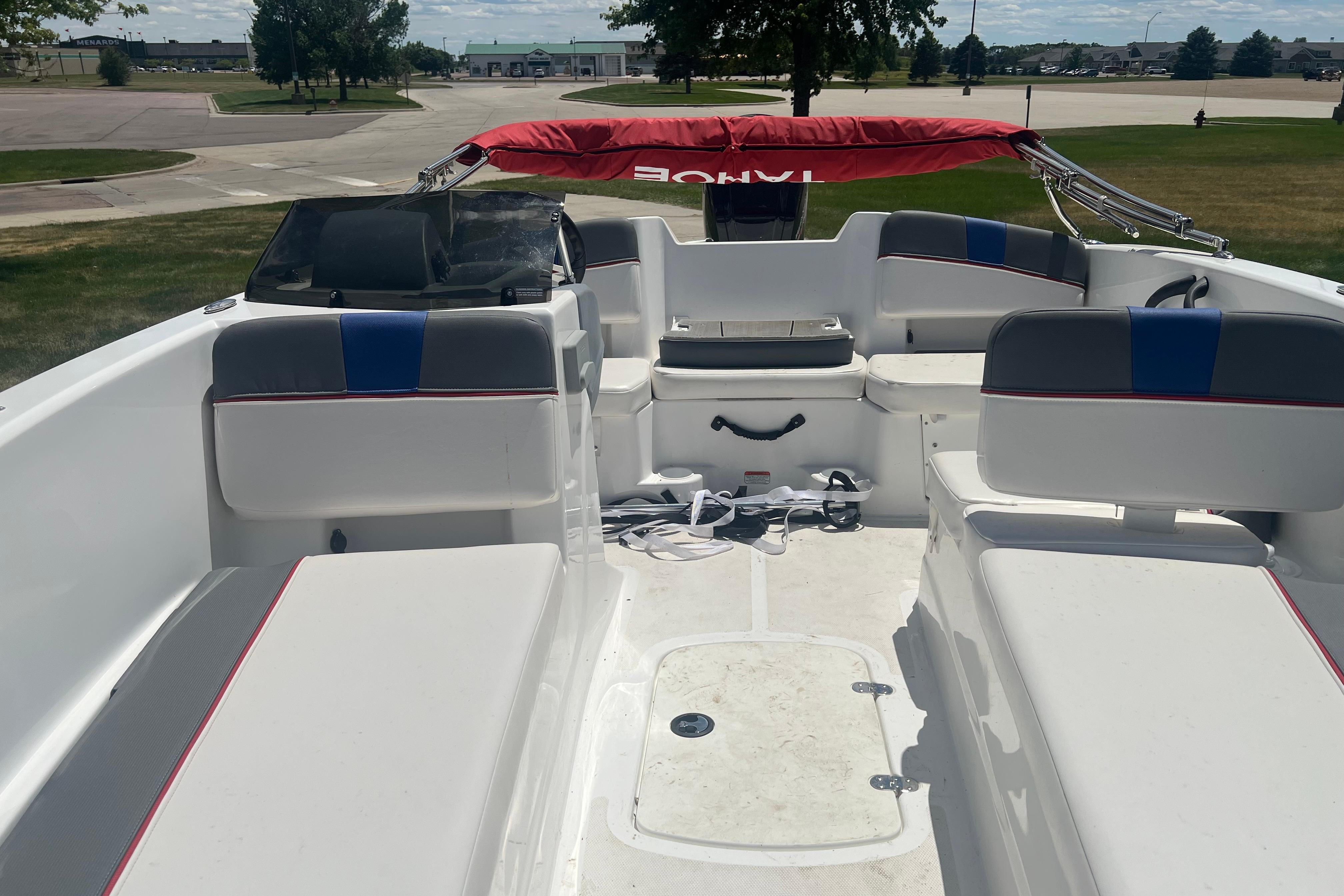 2023 Tahoe T18 boat interior with seating and red canopy in a parking area.
