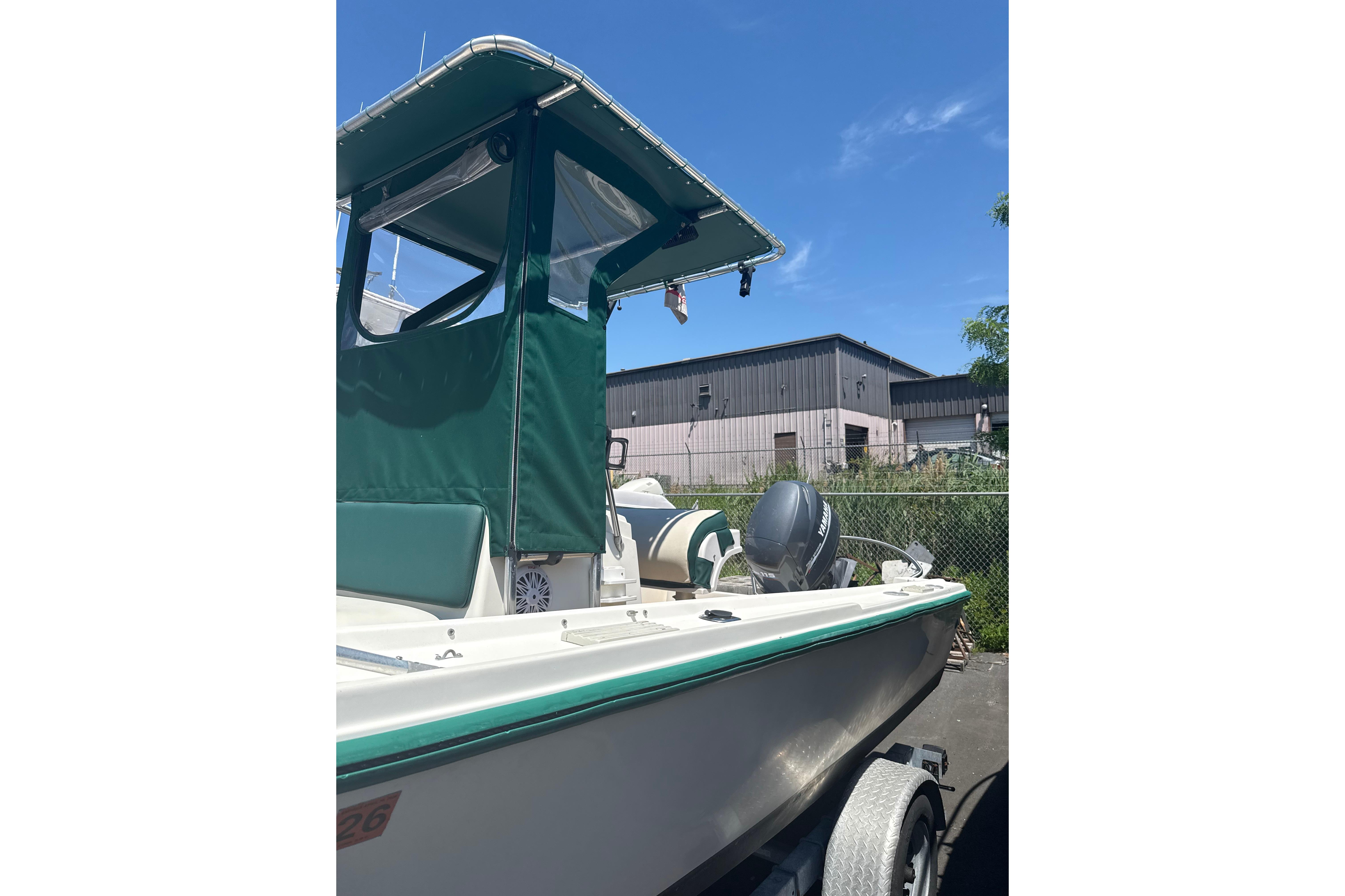 1982 Mako 20 Center Console boat with green canopy, parked on trailer under blue sky.