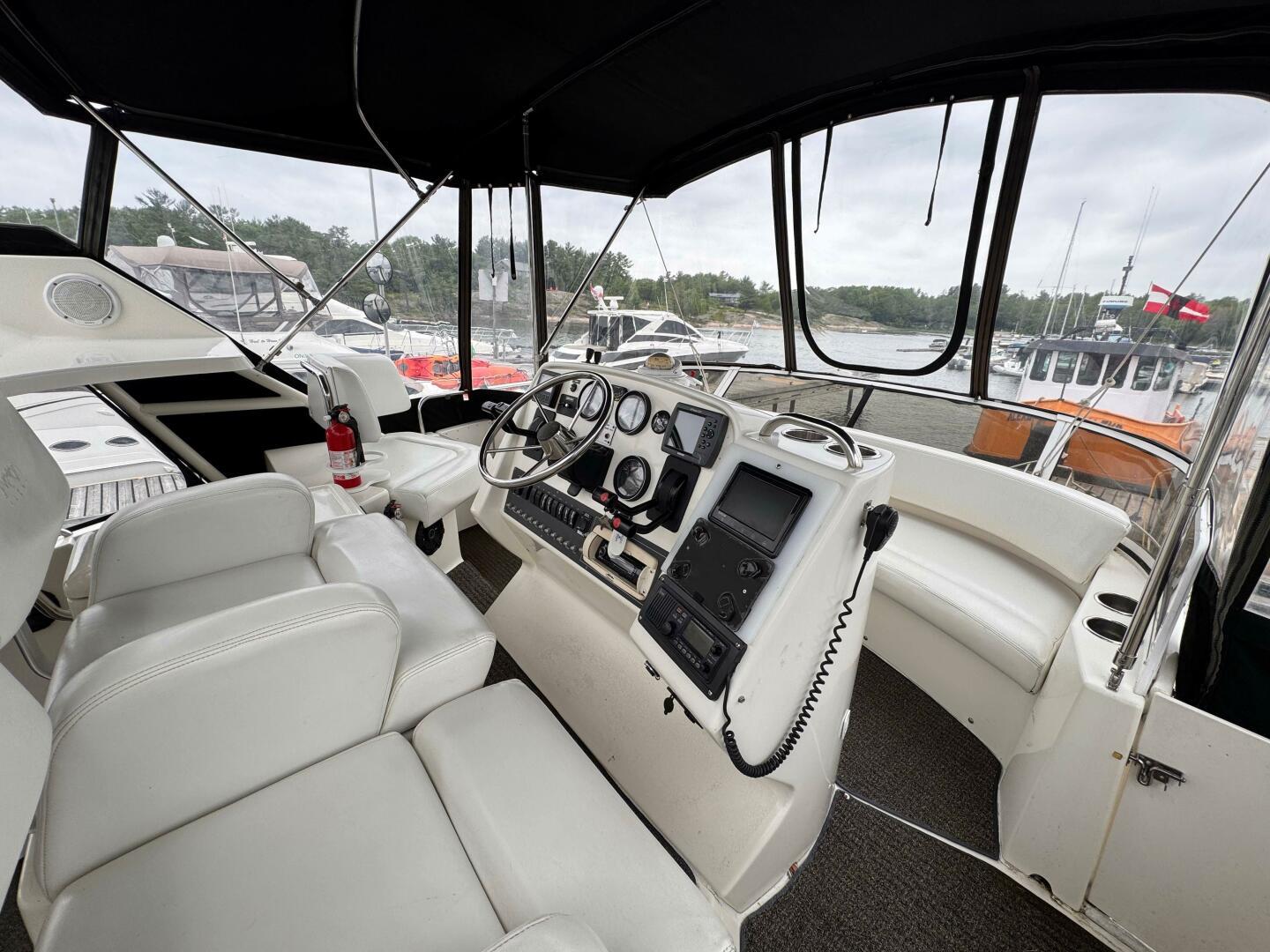1997 Silverton 352 Motor Yacht interior with helm, white seating, and marina view.