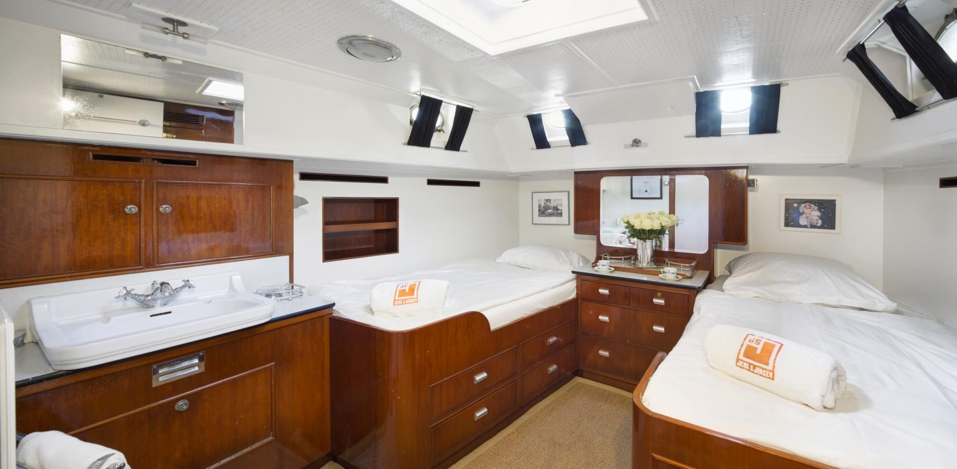 Luxurious cabin interior of 1958 Feadship ATALANTA J yacht with twin beds and wooden furnishings.
