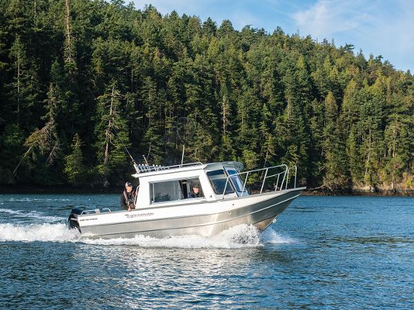 2023 Spartan 220 Maximus Pro boat cruising on a lake with forested background.