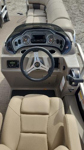 2023 Sun Tracker SportFish 22 DLX boat cockpit with steering wheel and beige seating.